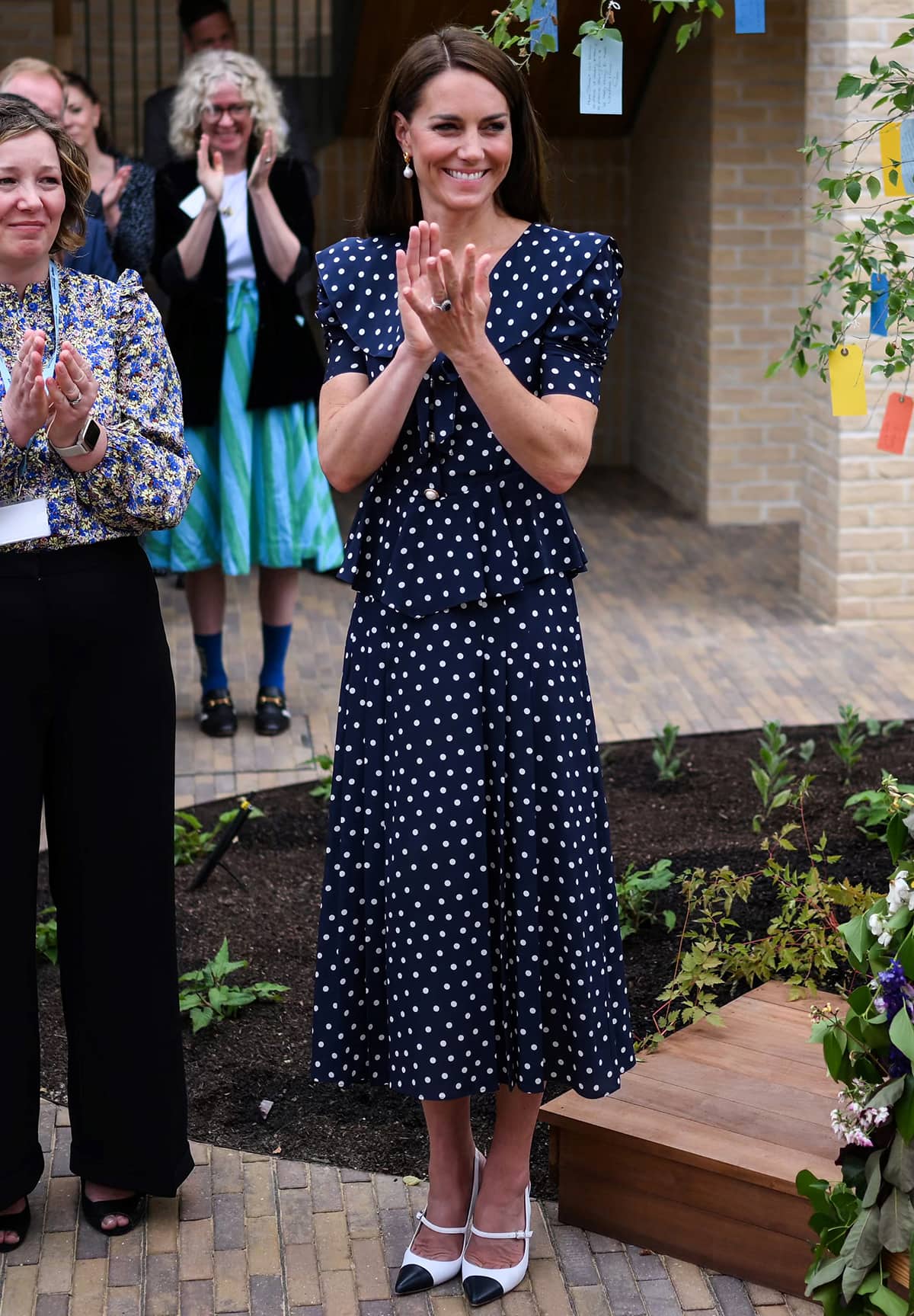 Kate Middleton wears a summer polka dot navy dress by Alessandra Rich with two-tone slingback pumps while visiting the Hope Street residential community in Southampton, Hampshire on June 26, 2023