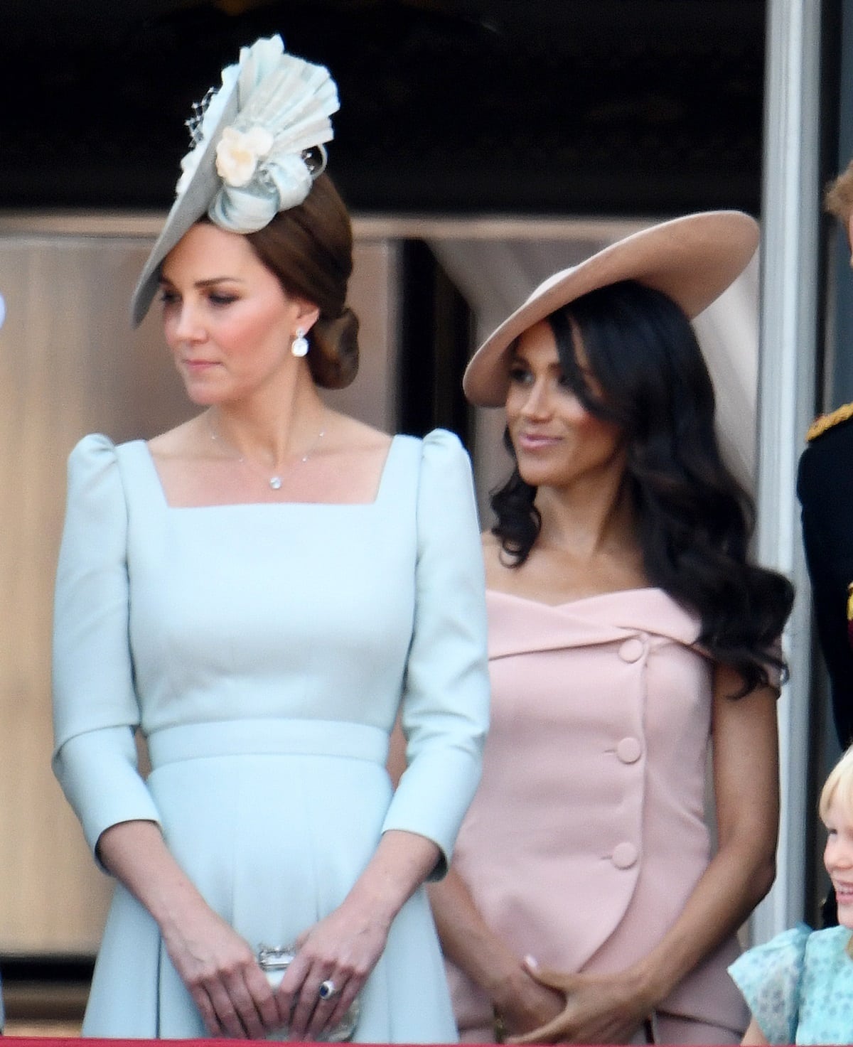 Kate Middleton, wearing a pastel blue Alexander McQueen dress with a coordinating fascinator, stands beside Meghan Markle, who is dressed in a blush pink Carolina Herrera ensemble during the Trooping the Colour ceremony in 2018