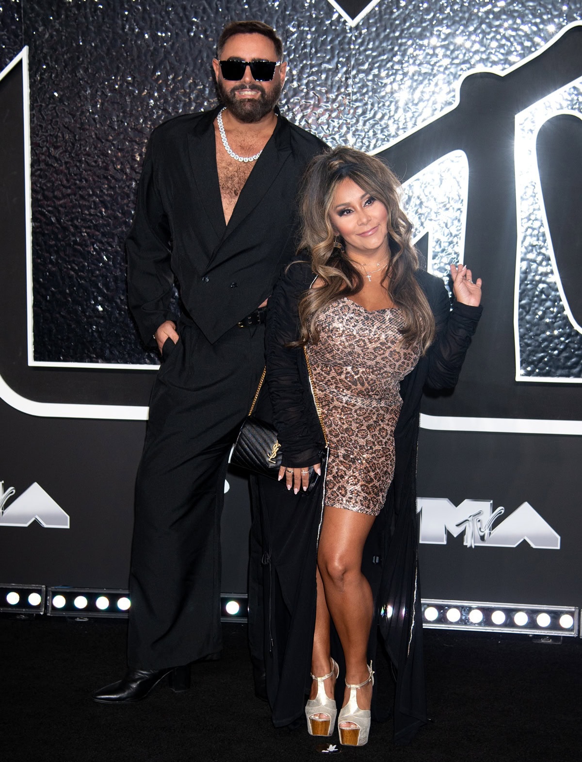 Nicole “Snooki” Polizzi looked tiny beside Joey Camasta as she rocked sky-high metallic platform heels with a leopard print mini dress, long black cardigan, and signature voluminous hairstyle on the 2024 MTV Video Music Awards red carpet