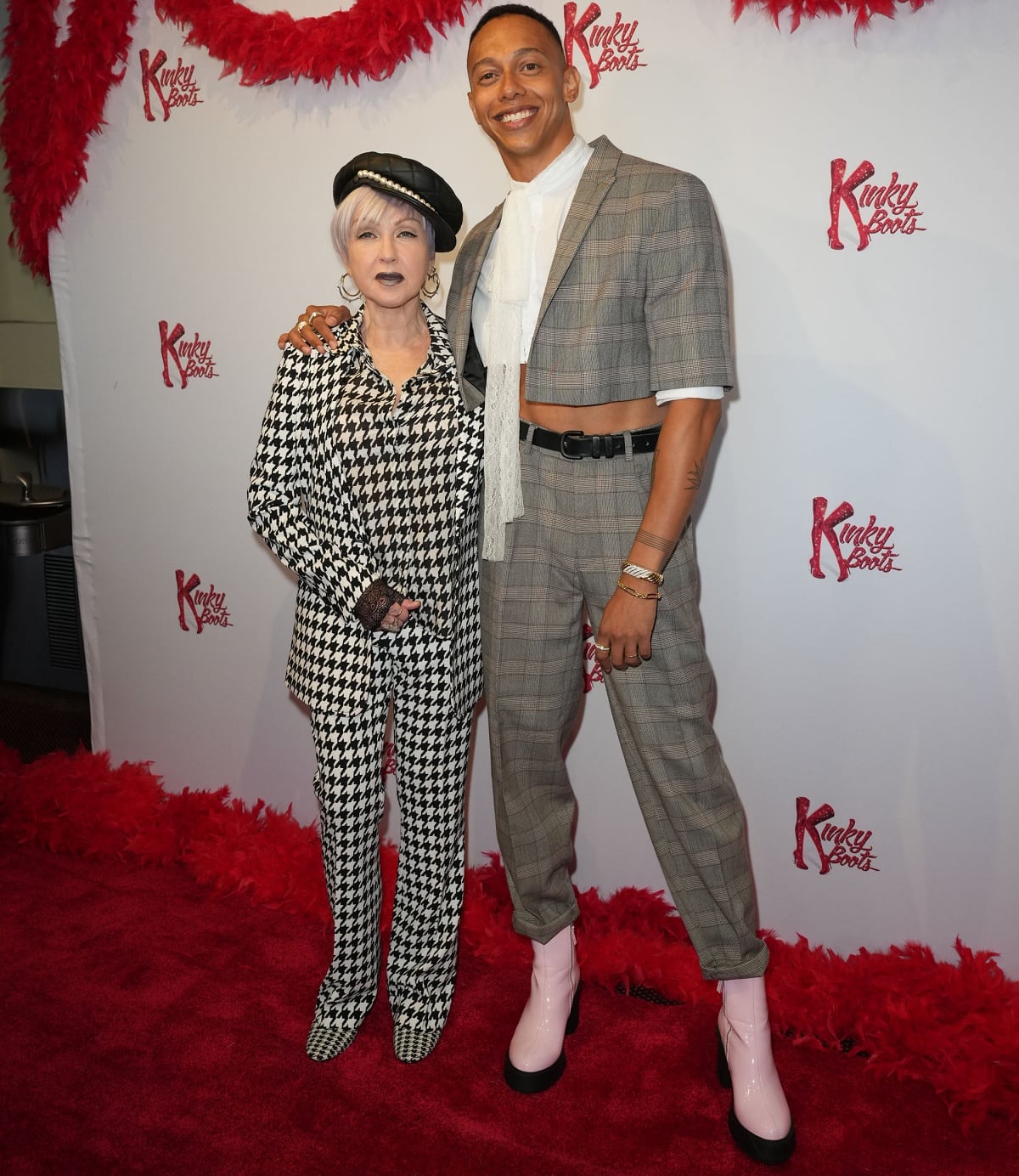 Cyndi Lauper's petite height contrasts sharply with Callum Francis' tall frame, both standing out in bold, patterned outfits at the Kinky Boots event