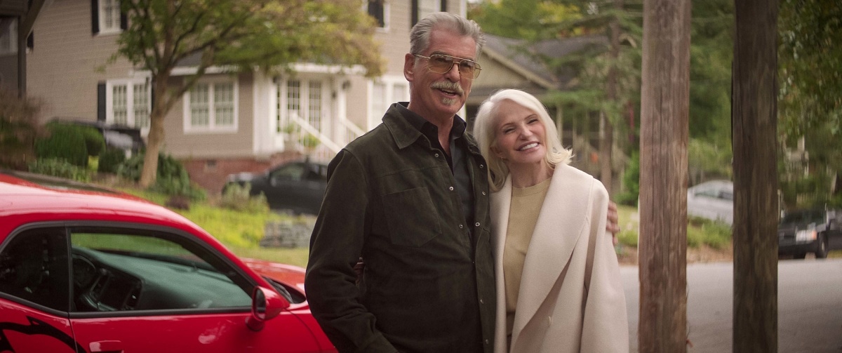 Pierce Brosnan and Ellen Barkin share a cozy moment as Billy and Lilly McDermott in The Out-Laws, bringing both charm and mischief to their roles as criminal in-laws