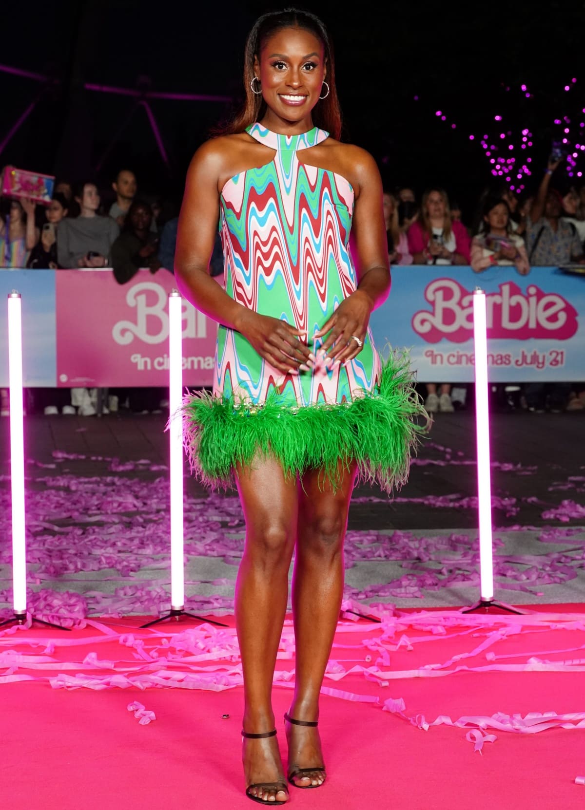 Issa Rae making a stunning entrance in a feathered pink-and-green Spring 2023 creation by PatBo with Piferi heels at the Barbie photocall