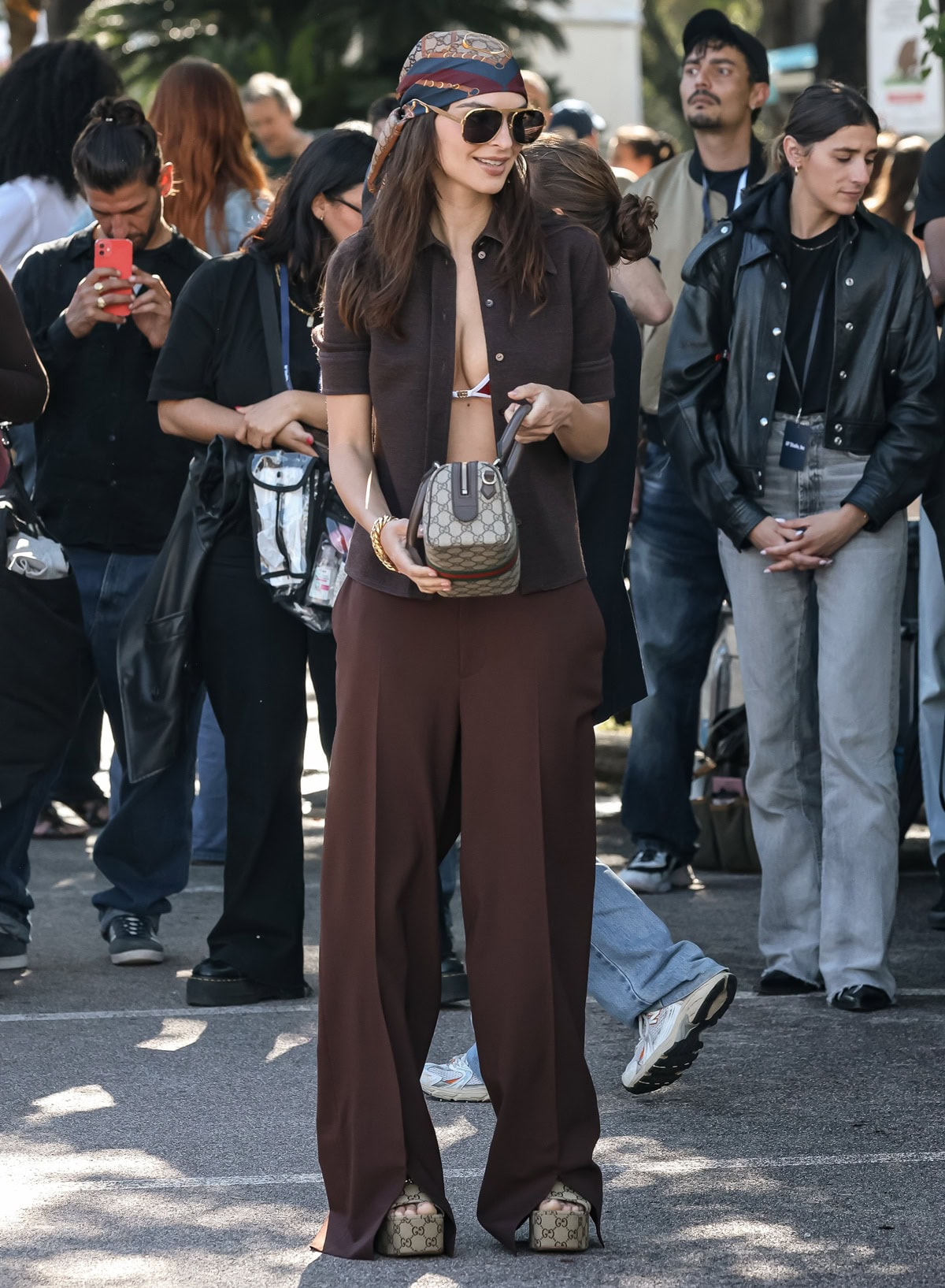 Emily Ratajkowski embraced retro glamour in a headscarf, wide-leg trousers, and brown Gucci platform mules featuring the brand’s signature GG monogram and horsebit detail while filming a campaign during the 2025 Cannes Film Festival