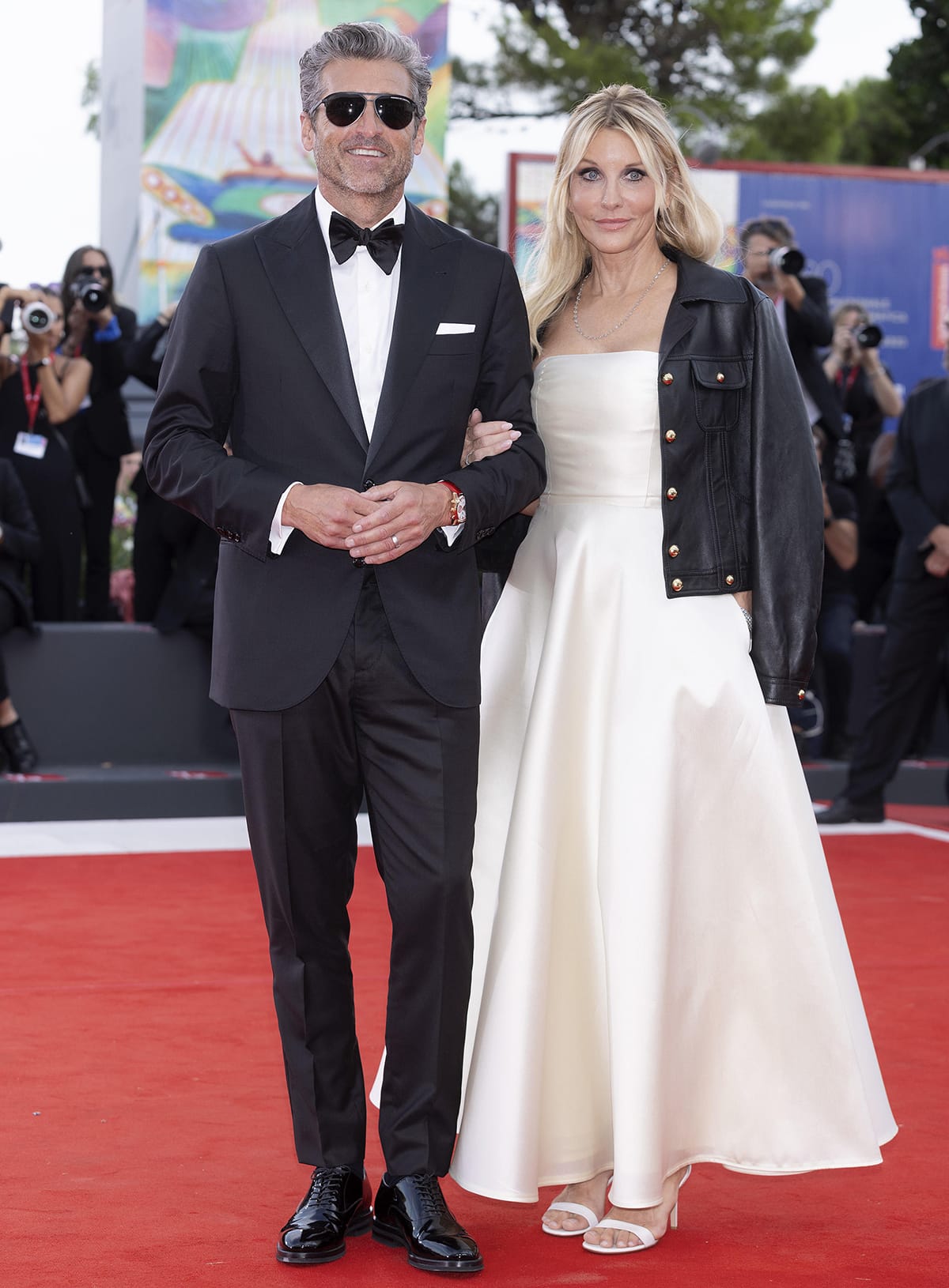 Patrick Dempsey opts for a classic three-piece suit with shiny dress shoes, a red watch, and sleek aviators