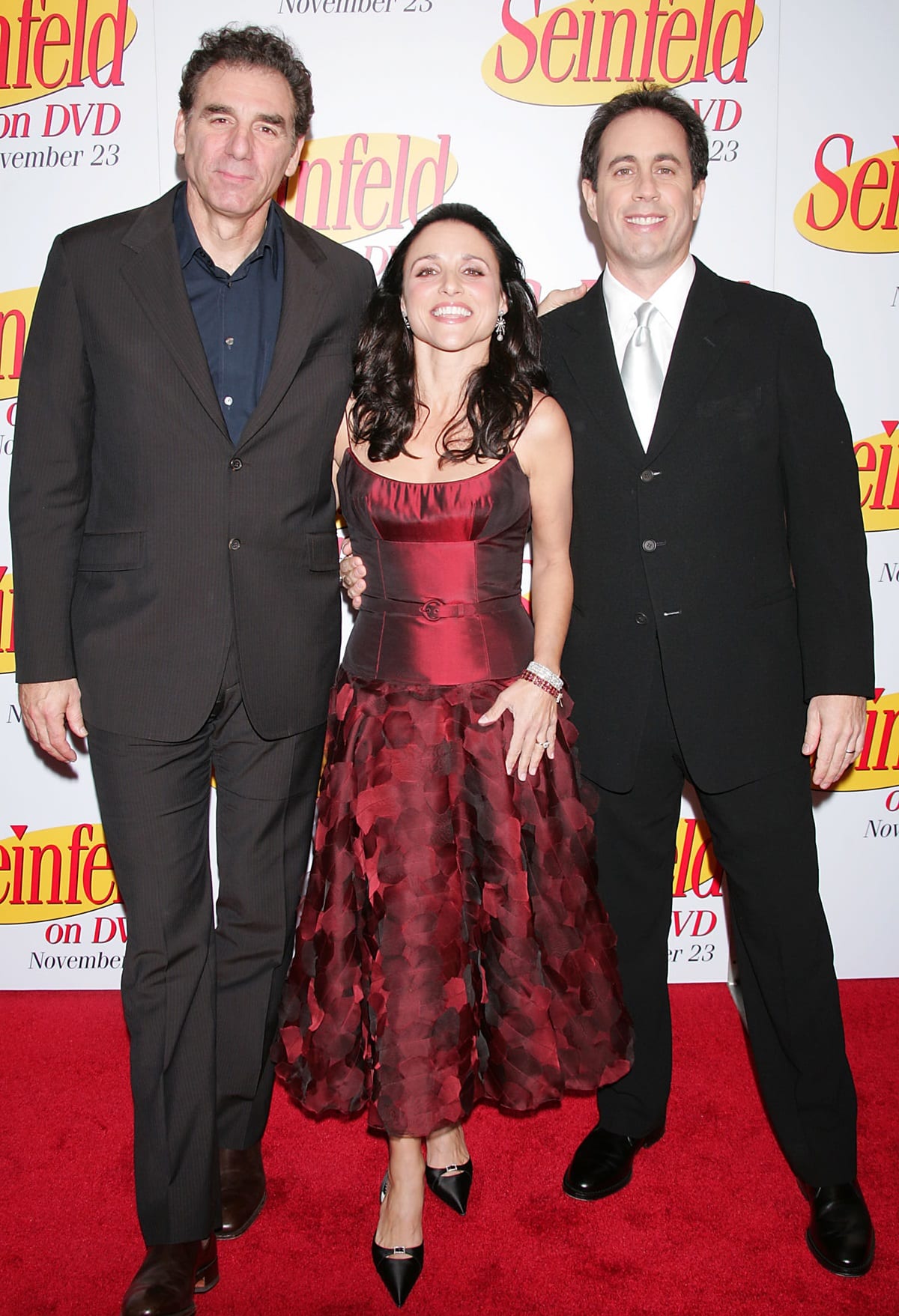 Michael Richards, Julia Louis-Dreyfus, and Jerry Seinfeld reunite in style at the Seinfeld DVD launch, with Julia shining in a rich burgundy dress while the men opt for classic suits