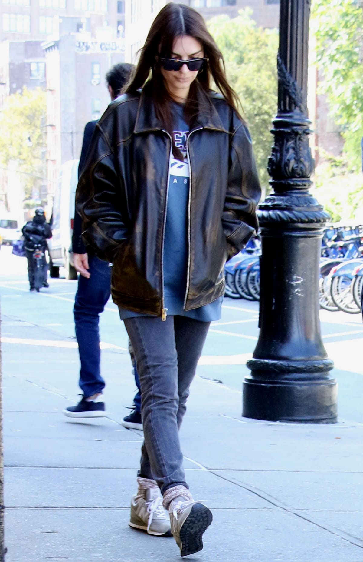 Emily Ratajkowski showing off her take on dadcore fashion with a distressed black leather jacket over an oversized sweatshirt with charcoal gray skinny jeans while out and about in New York City