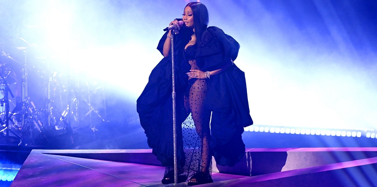 Nicki Minaj performed on stage in a voluminous black puffy coat over a black slip dress