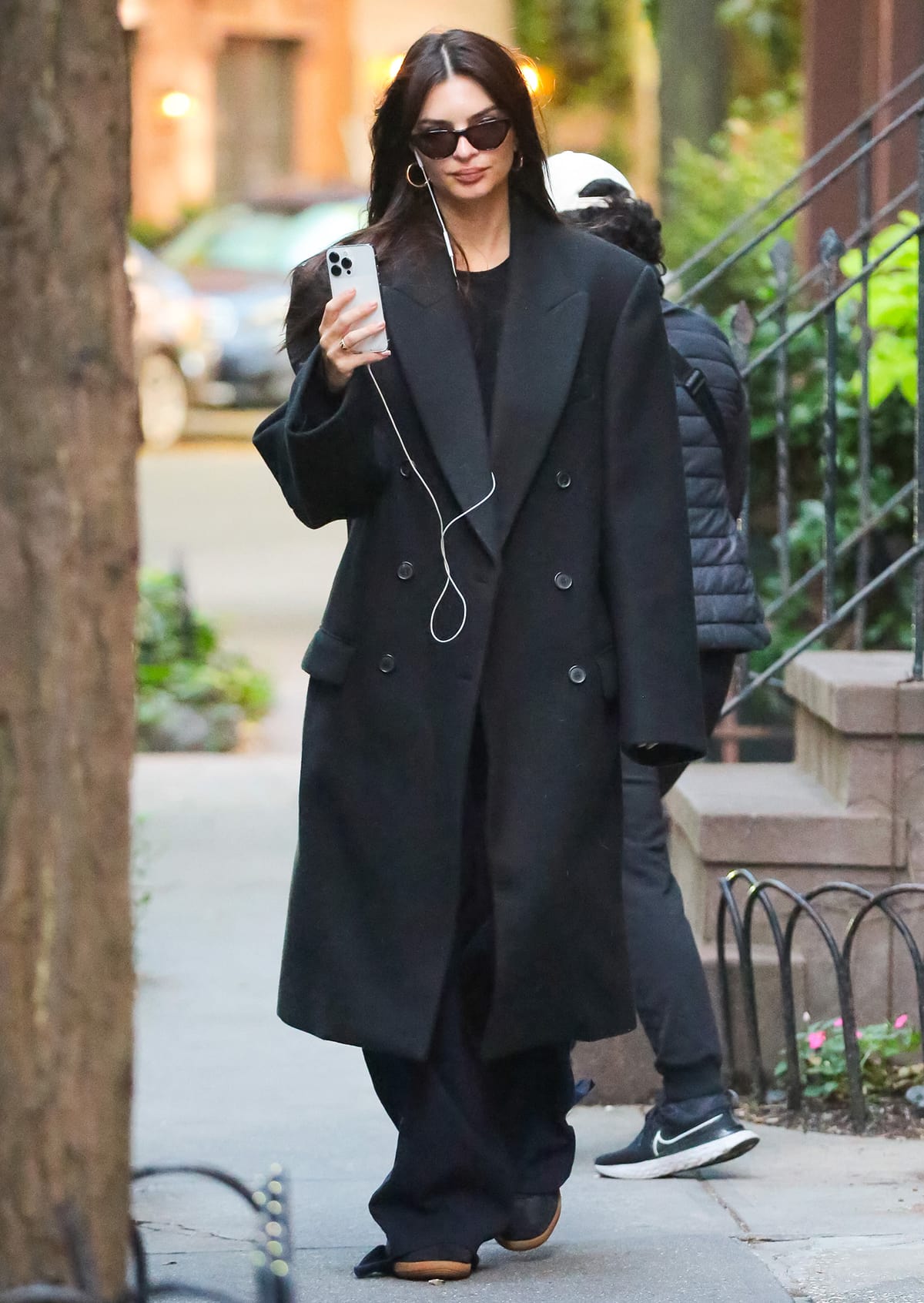 Emily Ratajkowski fully embraces dadcore fashion this fall in an oversized double-breasted coat with a black tee and baggy trousers on October 16, 2023