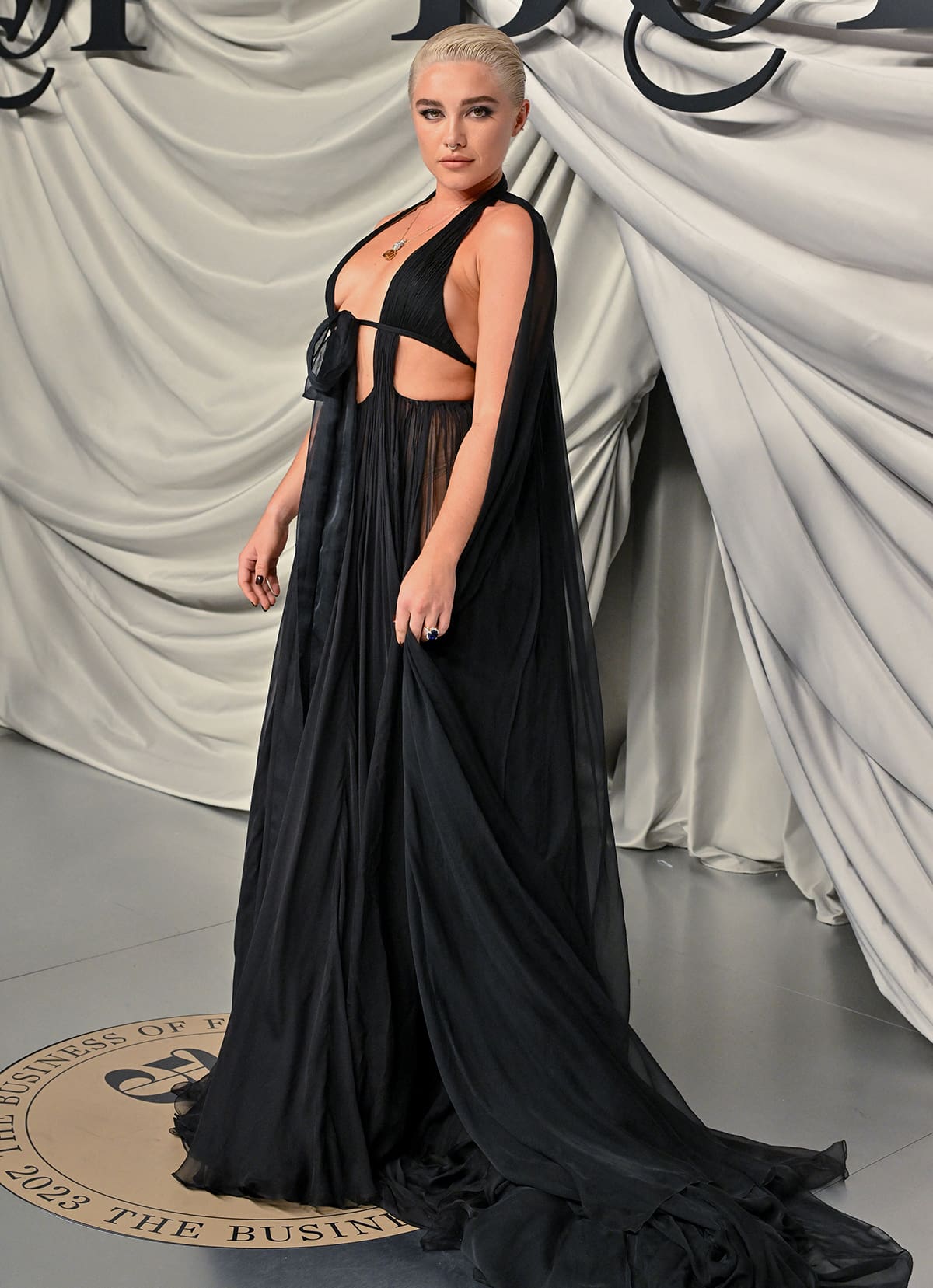 Florence Pugh flashes plenty of flesh in a sheer black Valentino gown with a bikini-style halter bodice, a tie front, and a flowing sheer skirt