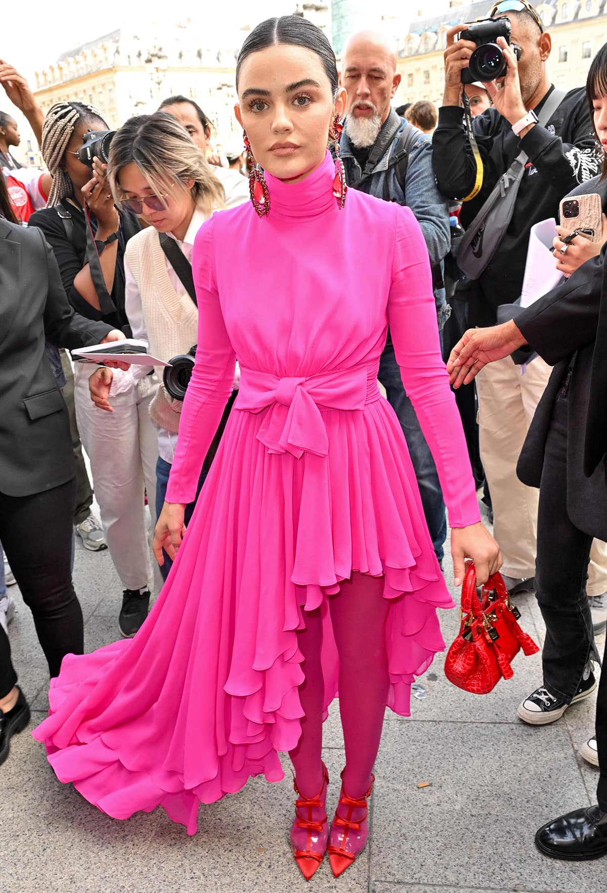 Lucy Hale stands out in a vibrant pink asymmetric draped silk jersey gown, Fuschia tights, and red heels at the Giambattista Valli Paris Fashion Week Womenswear Spring/Summer 2024 presentation on September 29, 2023