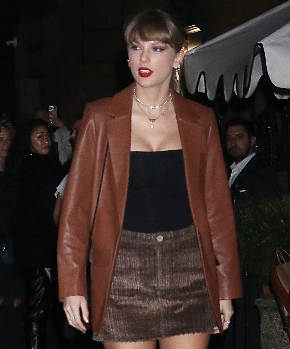 Taylor Swift completes her stylish fall look with gold jewelry, low ponytail, and vibrant red lipstick
