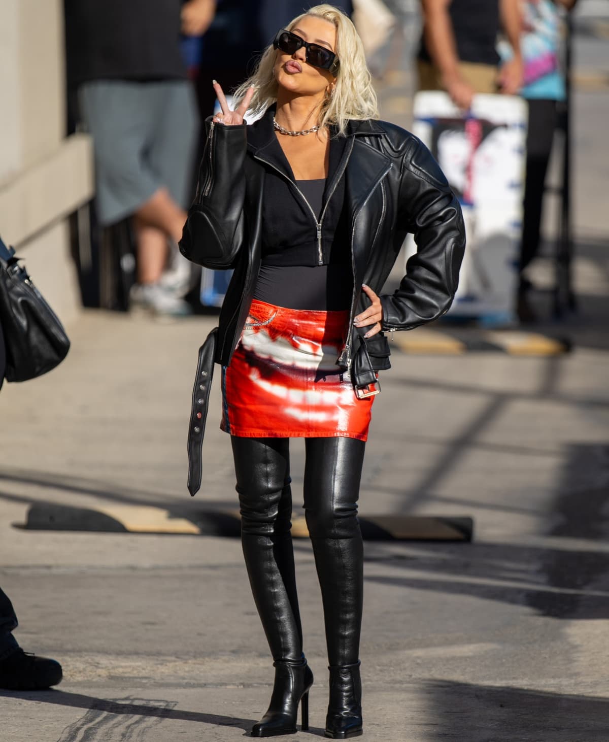 Christina Aguilera wearing an edgy ensemble featuring a Diesel red graphic print skirt and Saint Laurent black leather over-the-knee boots
