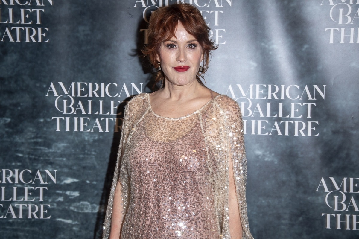 Molly Ringwald’s beauty look consisted of a chic updo, a vibrant red lip, and smoky eye makeup