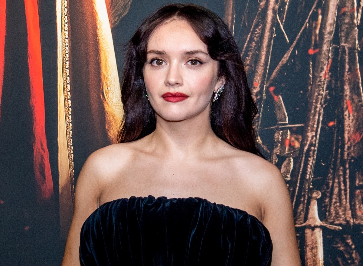 Olivia Cooke channels classic Hollywood glamour in a strapless black velvet gown, bold red lipstick, and sparkling emerald-accented earrings