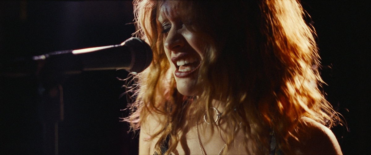 Olivia Cooke as Lou in Sound of Metal (2019), delivering a raw performance as a punk-metal vocalist — complete with smudged eyeliner, layered necklaces, and fierce emotional energy on stage