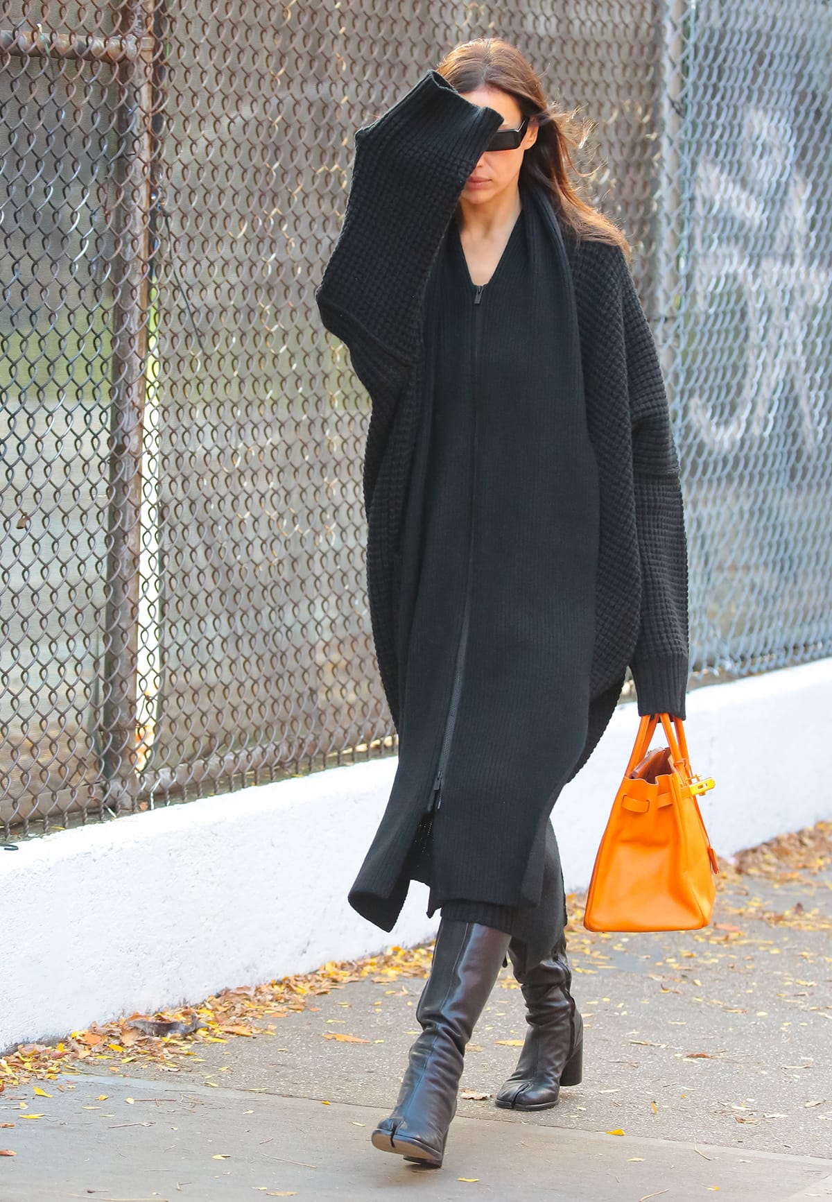 Irina Shayk opts for a monochromatic fall outfit composed of a thick black jacket, a black knit midi dress, and black knee-high boots while out in New York City on November 1, 2023
