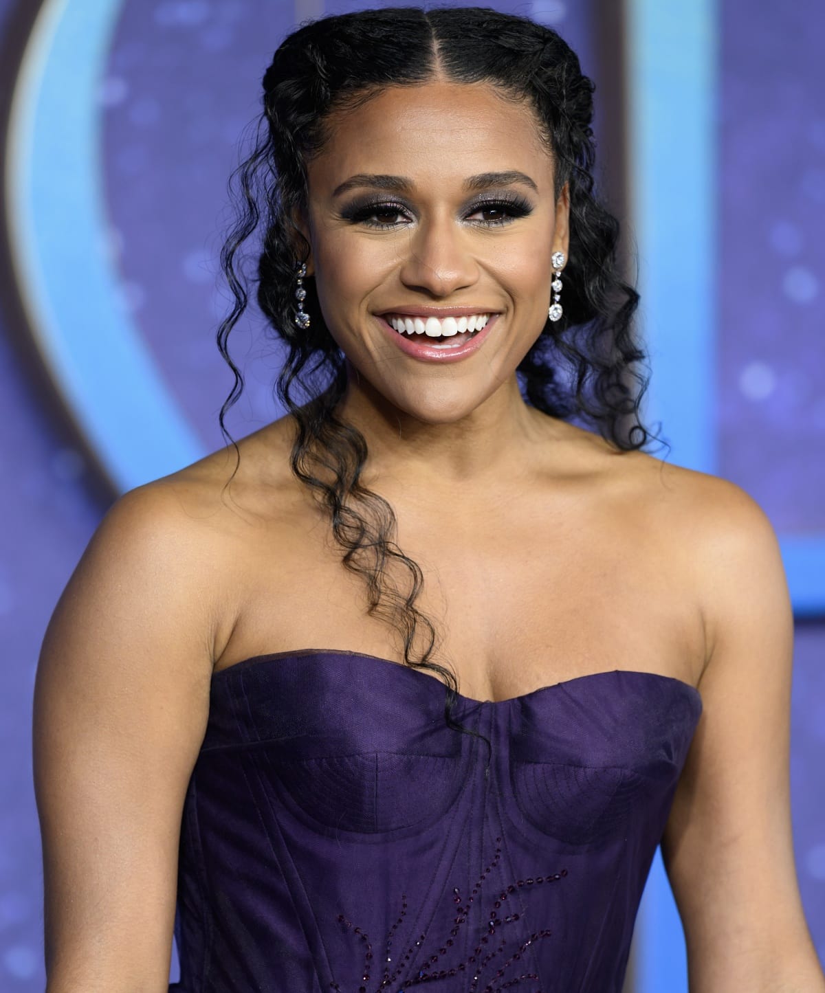 Ariana DeBose’s beauty look consisted of smokey eyes, a nude lip, dark hair styled in two braids, and silver dangling earrings