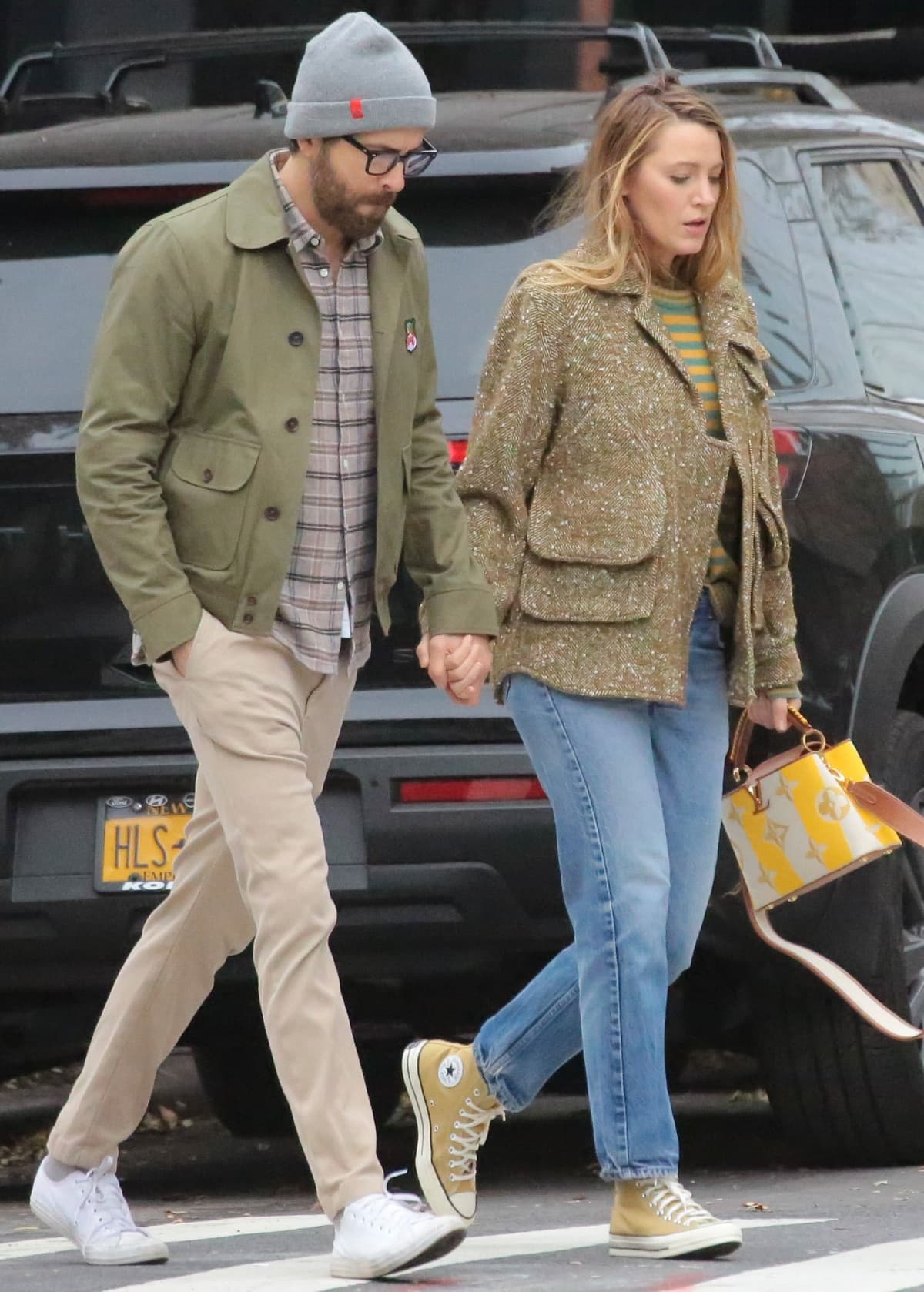 Blake Lively wearing a Smythe jacket layered over a green-and-yellow striped sweater with straight-leg jeans, yellow high-top Converse sneakers, and a Louis Vuitton Capucines BB bag