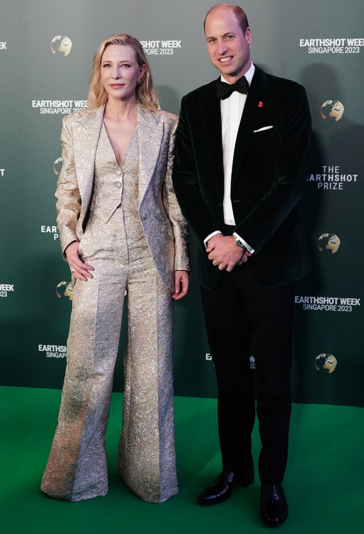 Cate Blanchett posing for photographs on the green carpet with Prince William in a classic black-and-white tuxedo