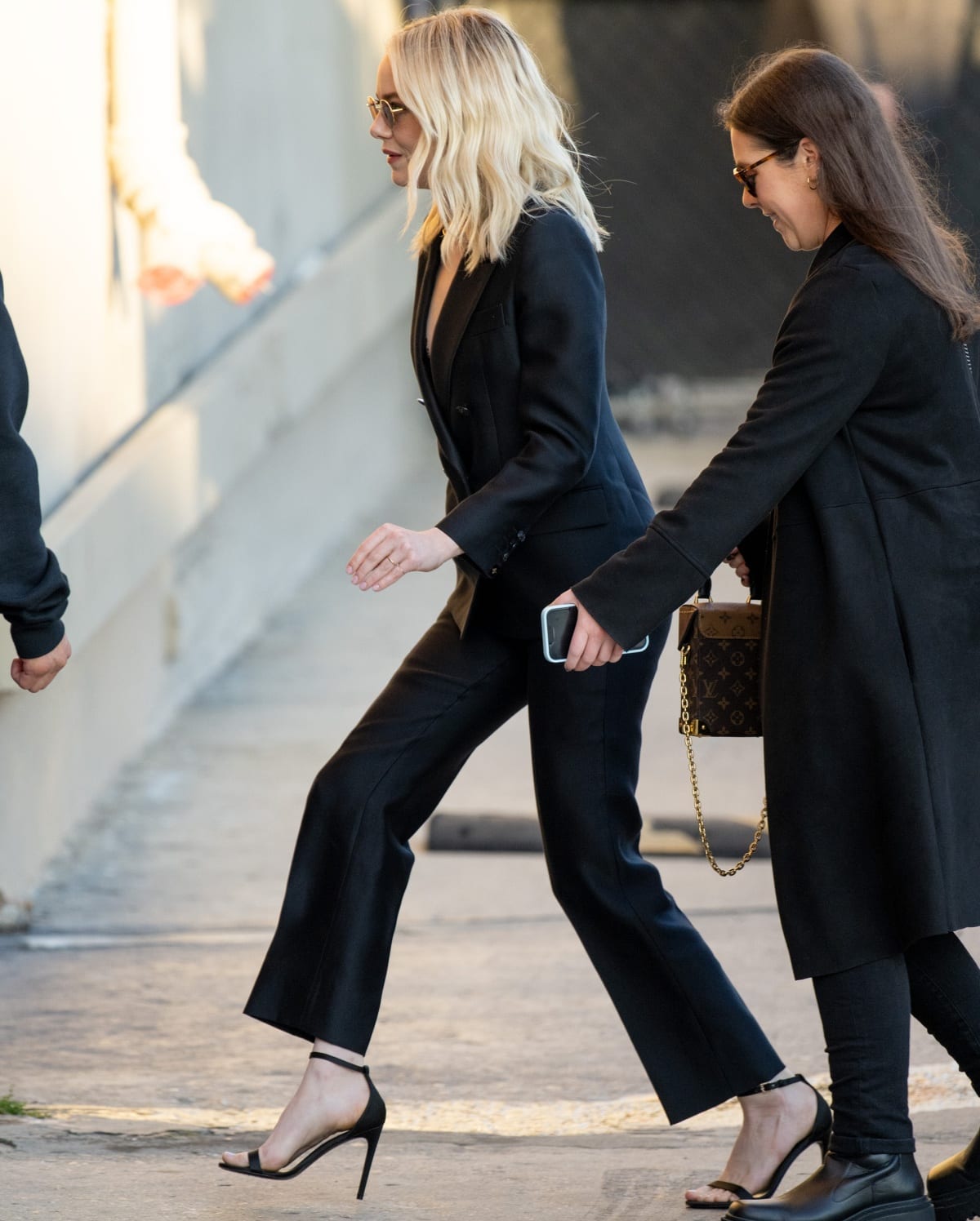 Emma Stone wearing a pair of strappy black heels with her black power suit