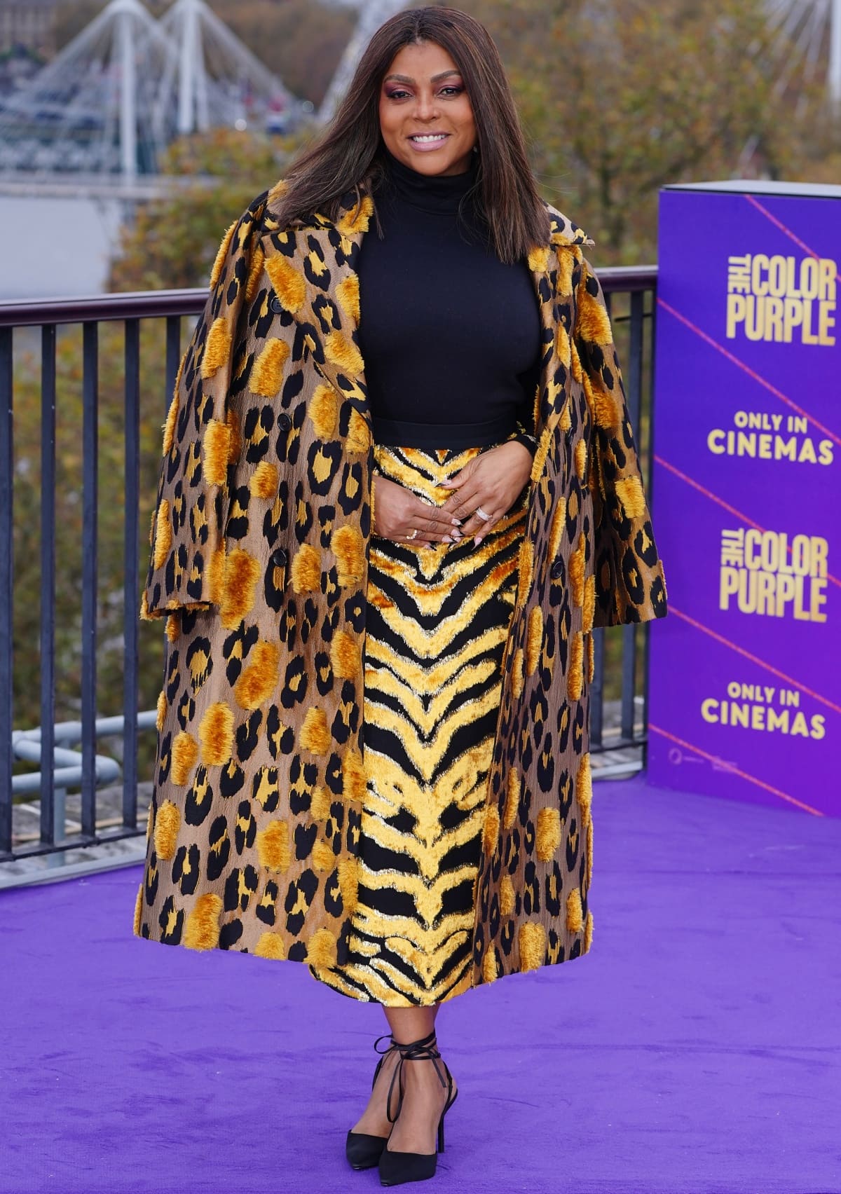 Taraji P. Henson wearing a mix of prints and hues in a Roberto Cavalli Fall 2022 ensemble featuring a black turtleneck with a zebra-print skirt and a leopard-print coat at the photocall for the cast of The Color Purple in London