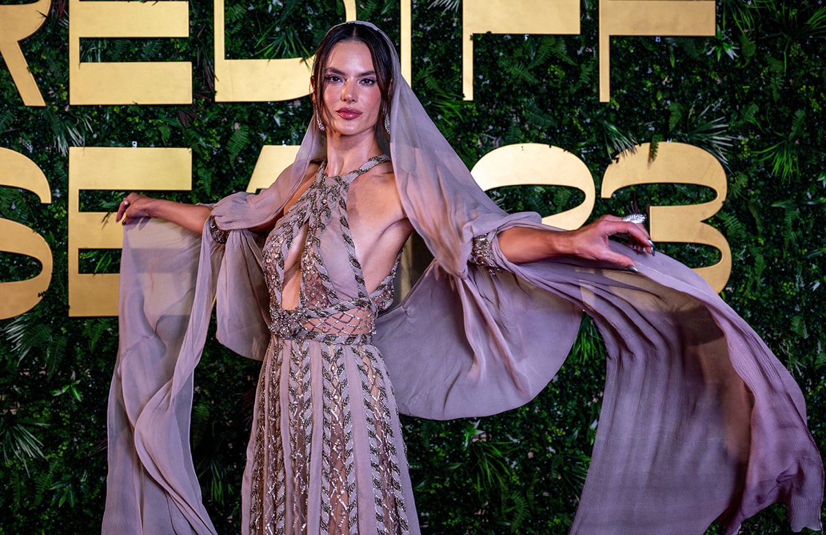 Alessandra Ambrosio showcases her flair in a sheer cutout halter gown with a sheer headscarf, reminiscent of the hooded gowns in the 1980s
