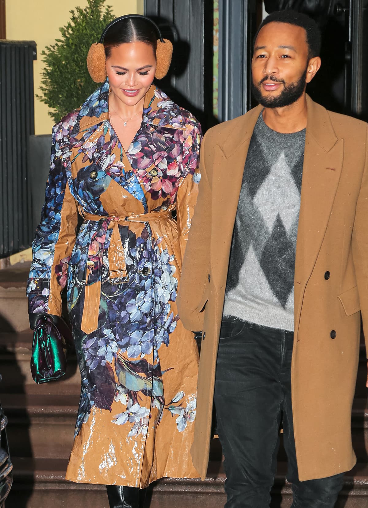 Chrissy Teigen is hard to ignore in her tan Dries Van Noten hydrangea-printed water-repellent trench coat and matching earmuffs while out and about New York City