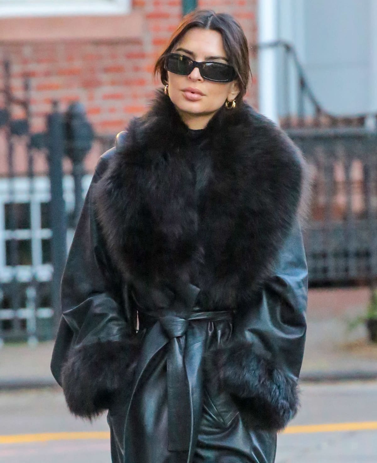 Emily Ratajkowski adds glitz to her all-black winter outfit with thick gold hoops and shields her eyes with Dolce & Gabbana Edition sunnies