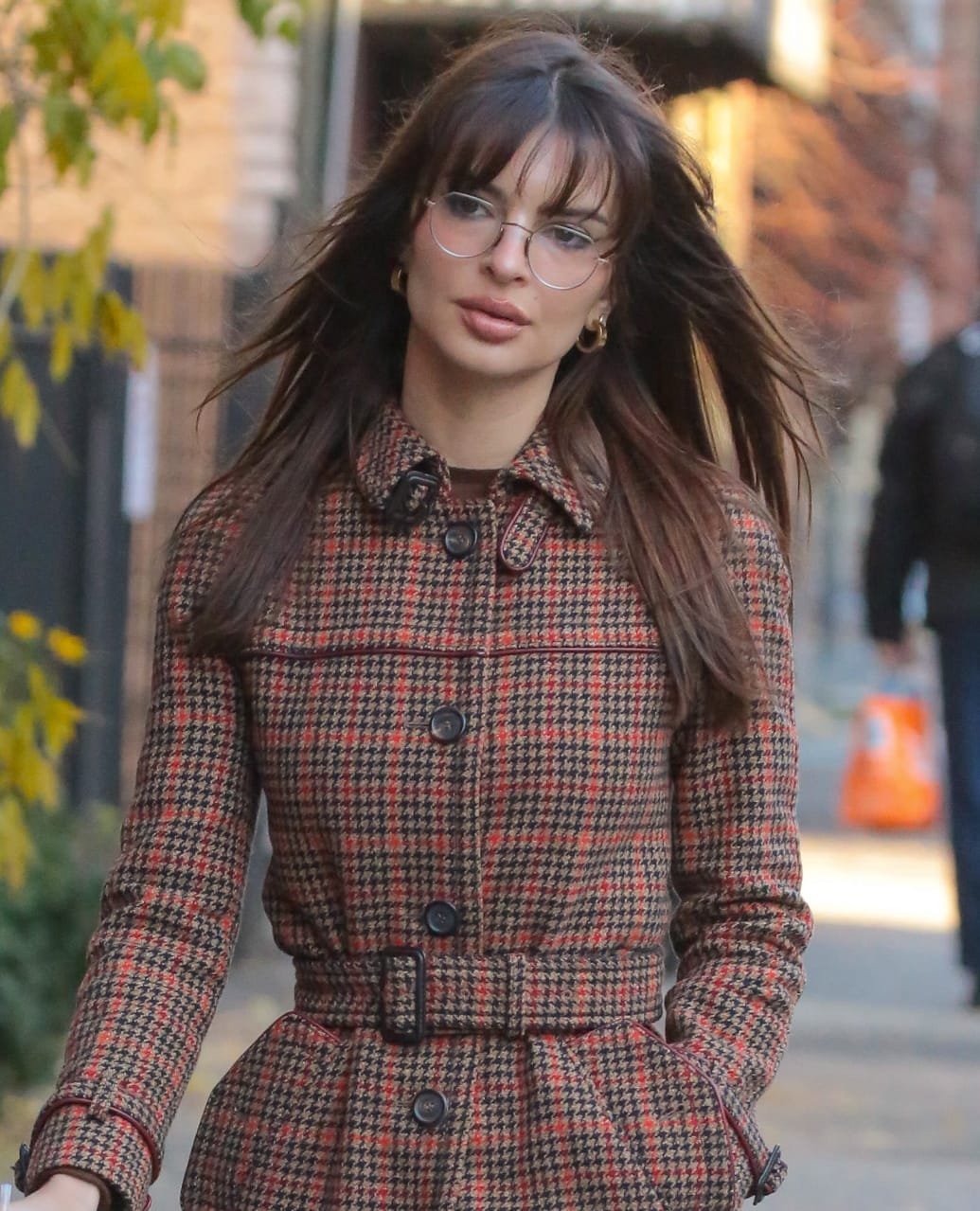 Emily Ratajkowski brings a sultry finish to her winter ensemble by wearing prescription glasses and letting her brown hair fall loosely around her shoulders