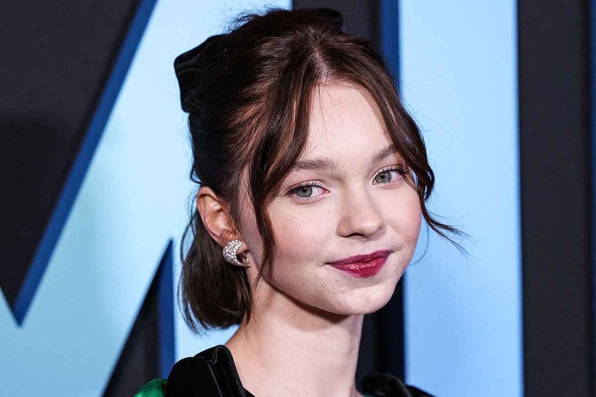 Emma Myers looks girly with her half-up ponytail, velvet bow, and berry lip color