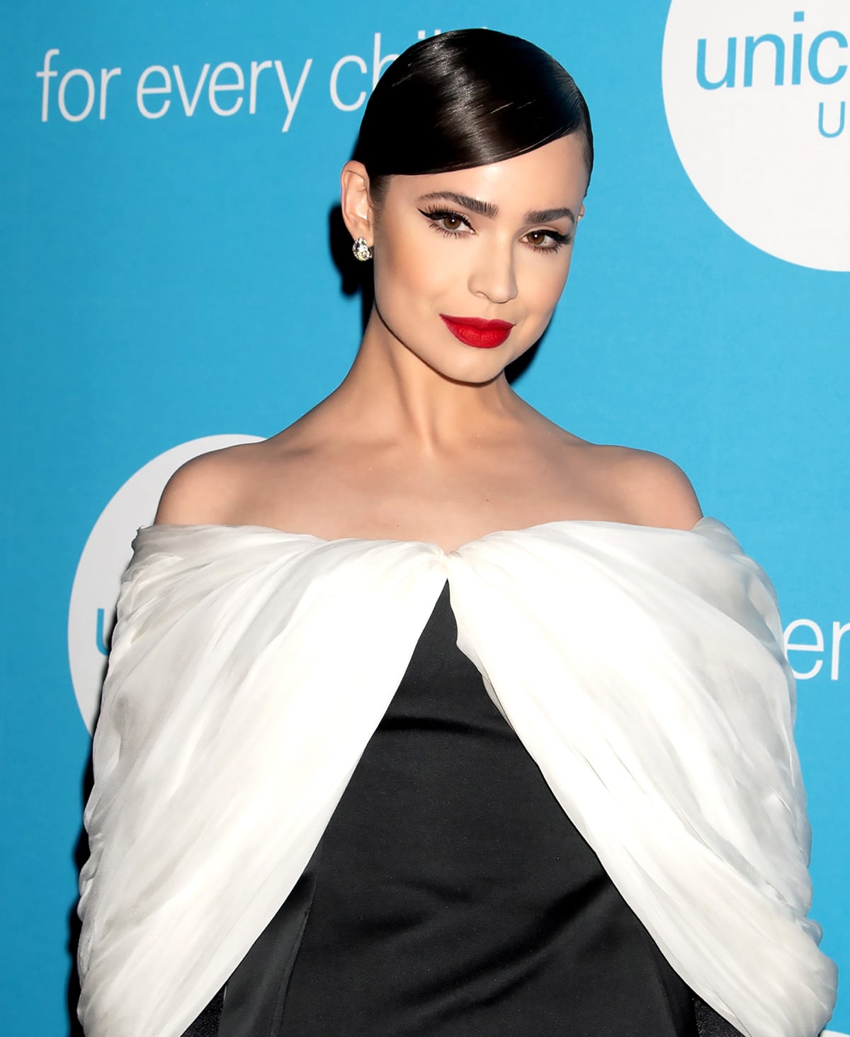 Sofia Carson opts for old Hollywood glam with a side-parted bun and a swipe of bold red lipstick