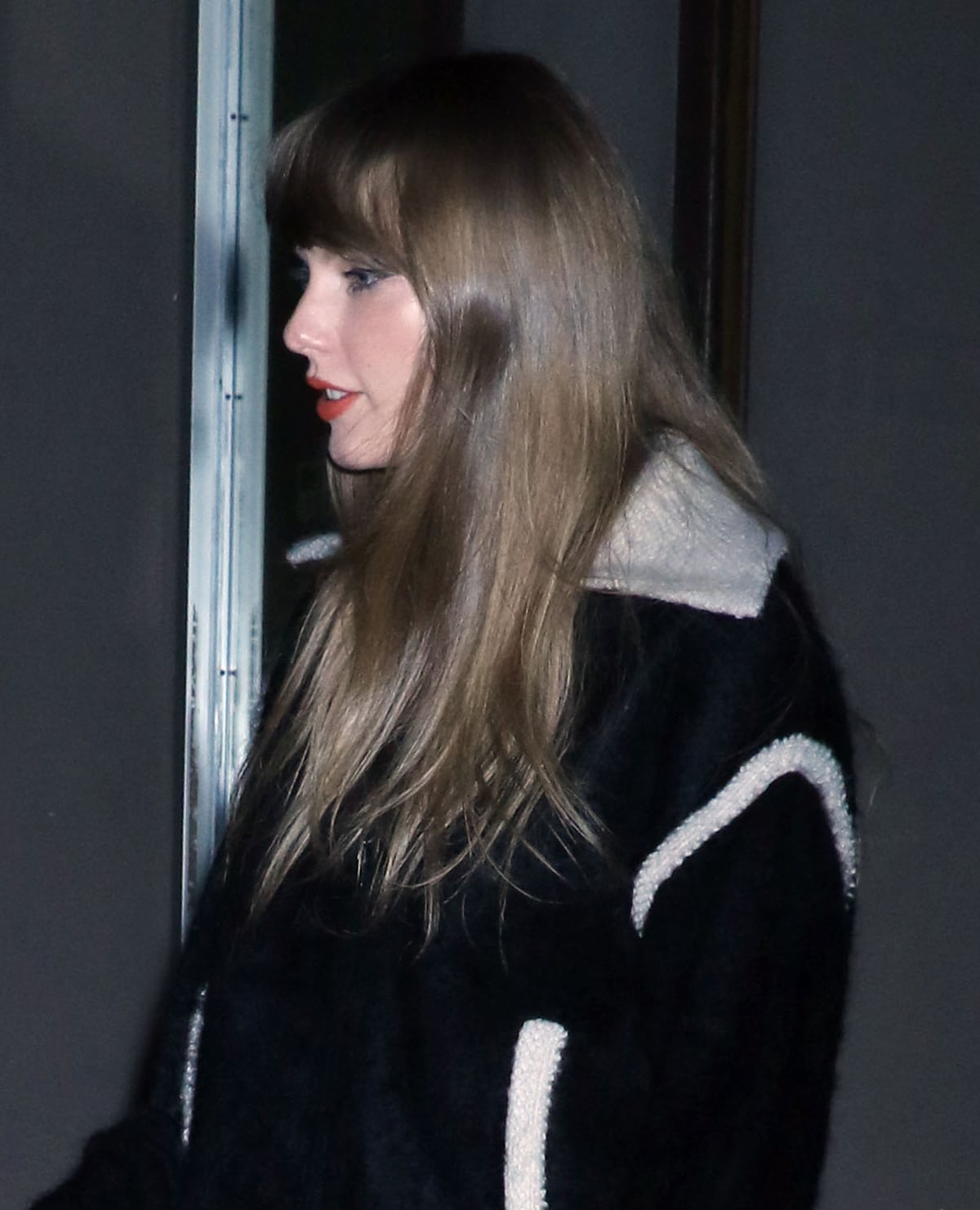 Taylor Swift styles her honey-blonde hair down and wears her signature makeup look complete with mascara and red lipstick