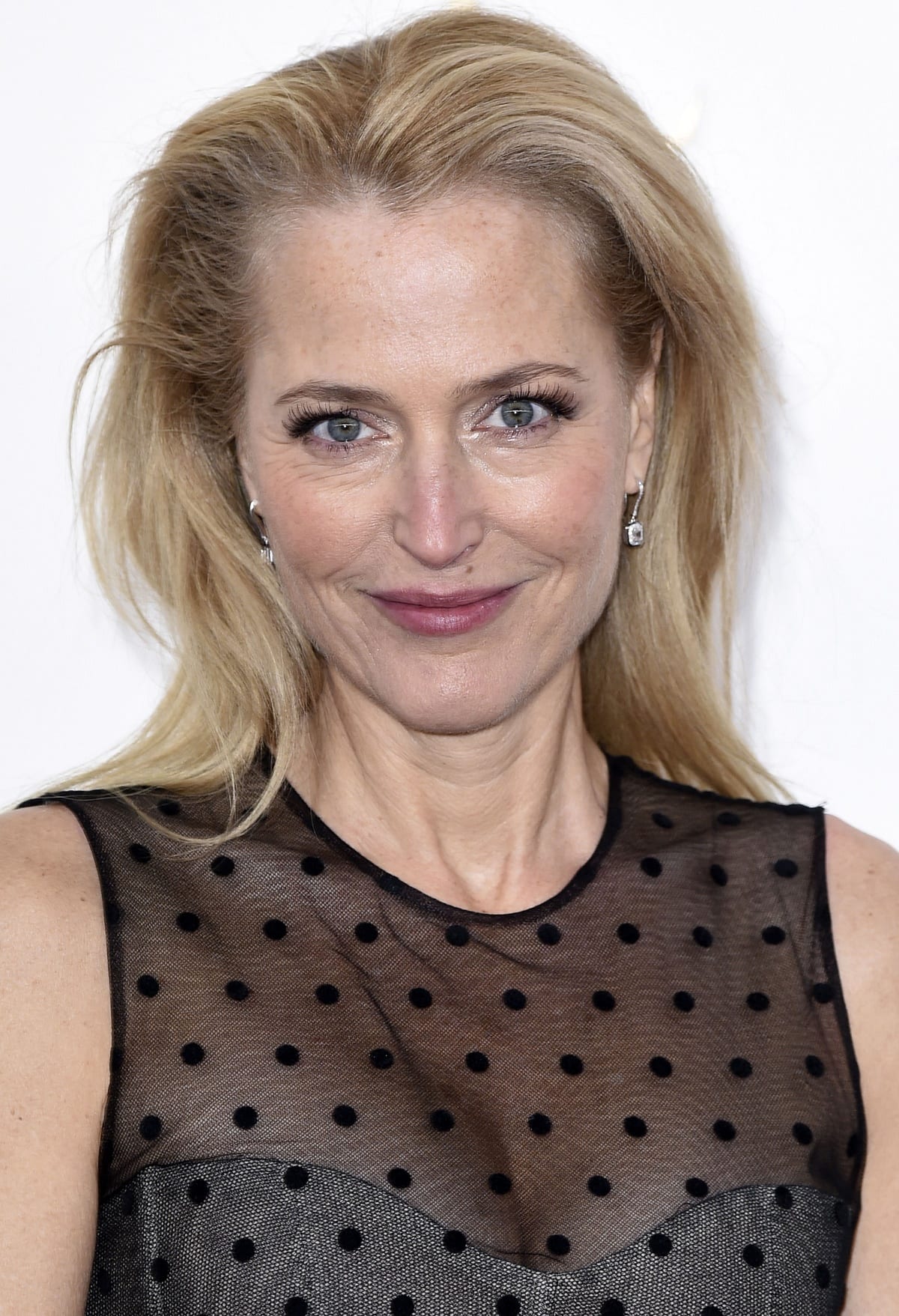 Gillian Anderson’s beauty look consisted of minimal makeup, blonde locks swept to one side, and simple dangly earrings