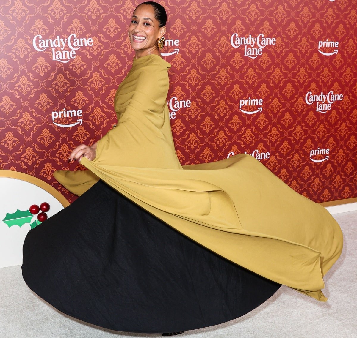 Tracee Ellis Ross making a dramatic return to the red carpet in a mustard-yellow top with cape sleeves that doubled as a long train, creating a mesmerizing effect as she moved while posing for photographs at the premiere of Candy Cane Lane