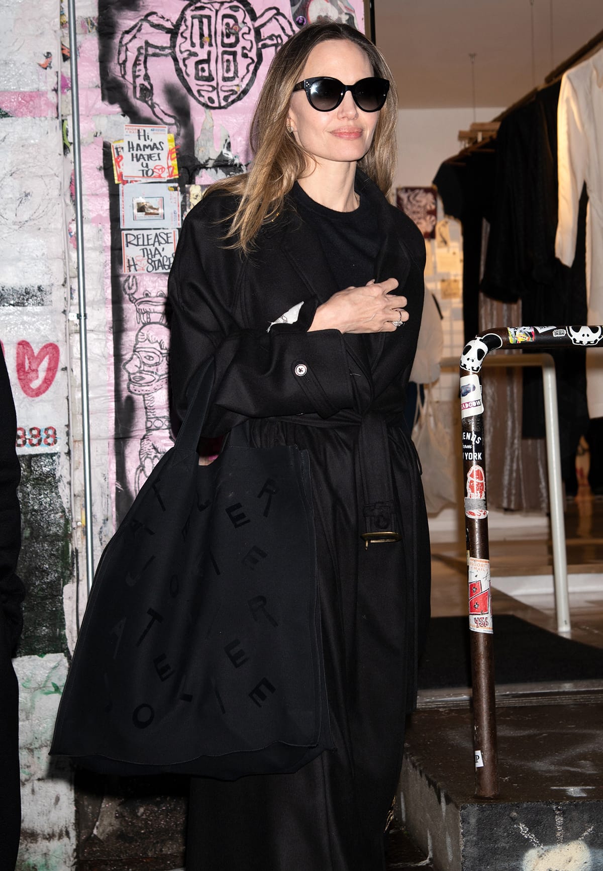 Angelina Jolie keeps her look coordinated by styling her all-black ensemble with a large black Atelier Jolie tote and a pair of black Celine sunglasses