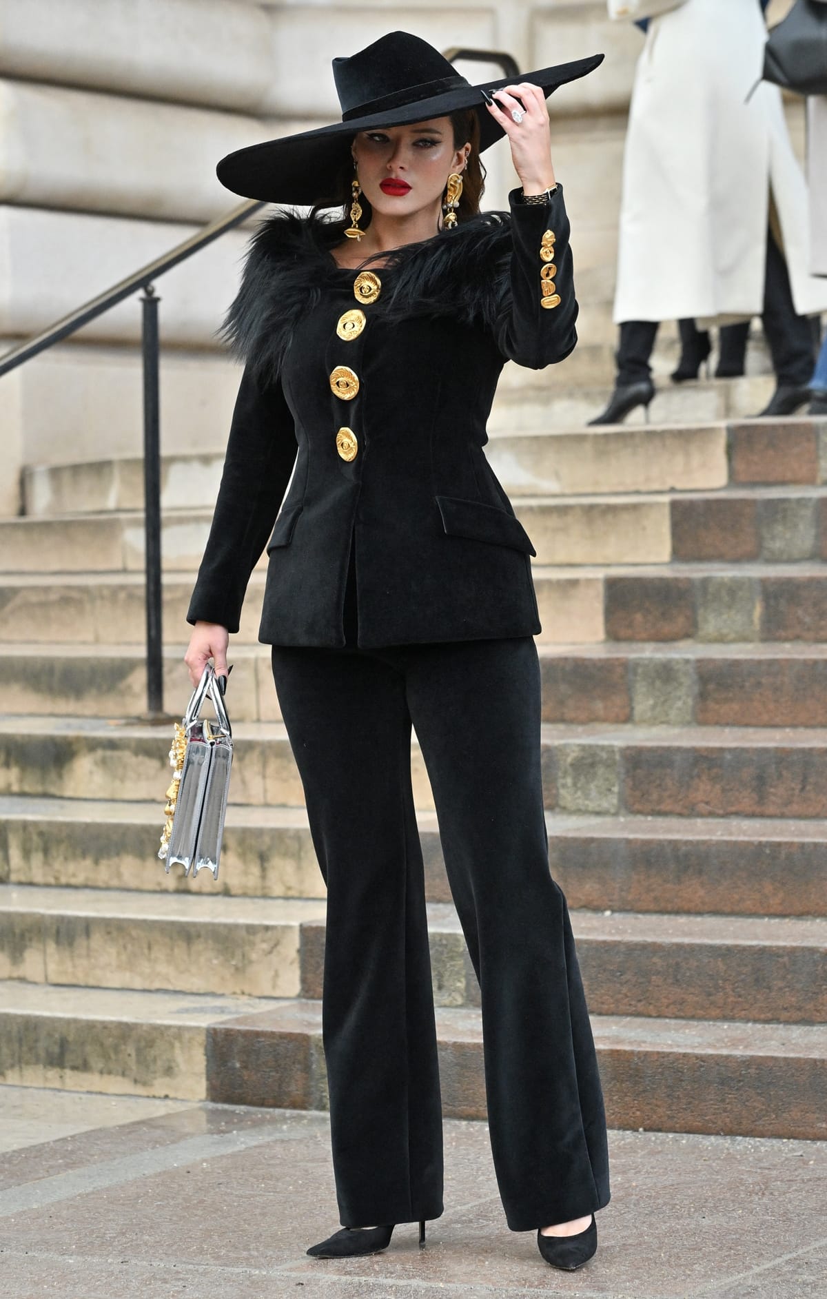 Bella Thorne showcases her sophisticated side in a fitted black velvet Schiaparelli pantsuit, accented with bold gold details and dramatic earrings at the Schiaparelli Spring/Summer 2024 show during the Haute Couture Spring/Summer 2024 as part of Paris Fashion Week on January 22, 2024 in Paris, France