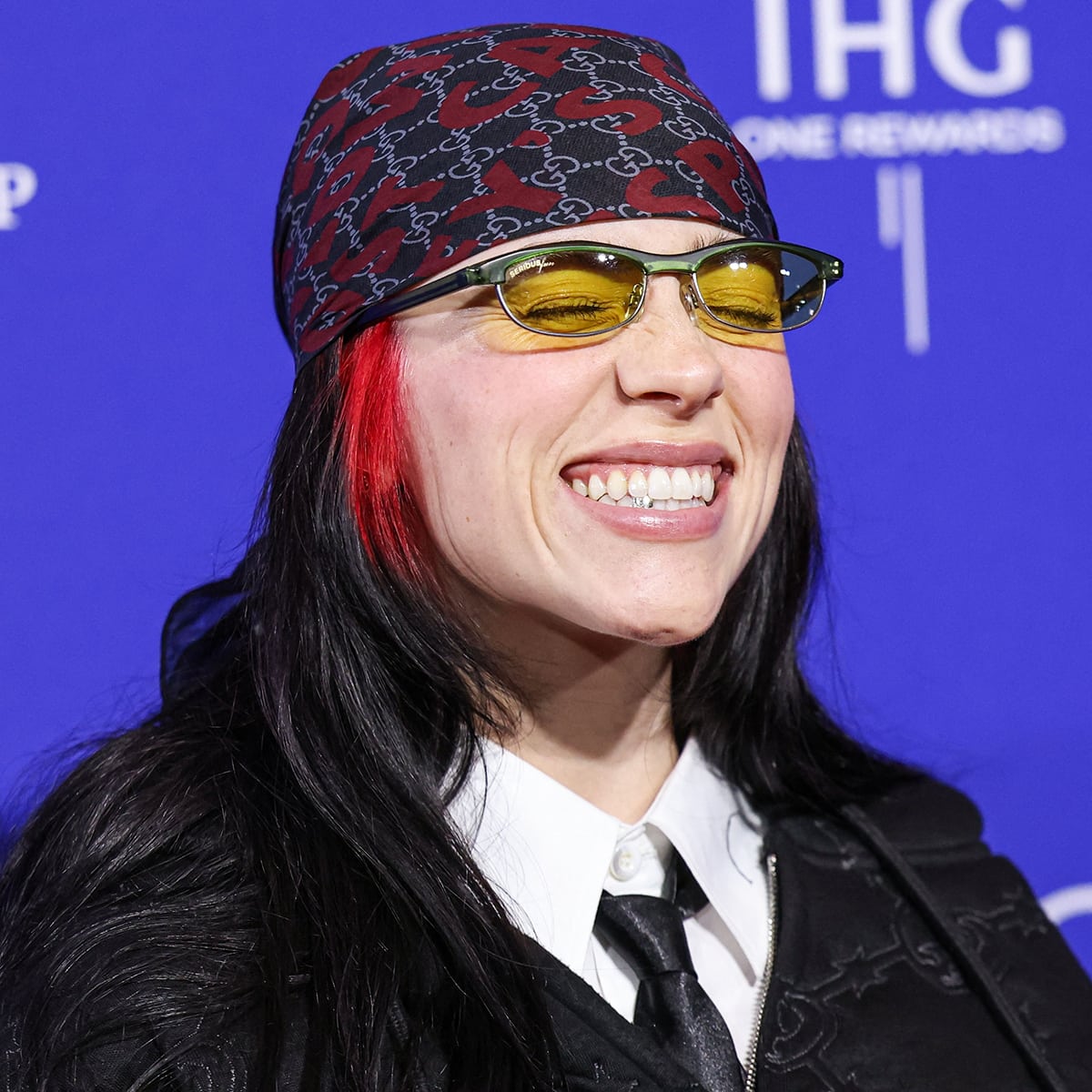 Billie Eilish styles her look with a red and black Gucci headscarf and a pair of Alpina Chillout yellow-tinted sunglasses