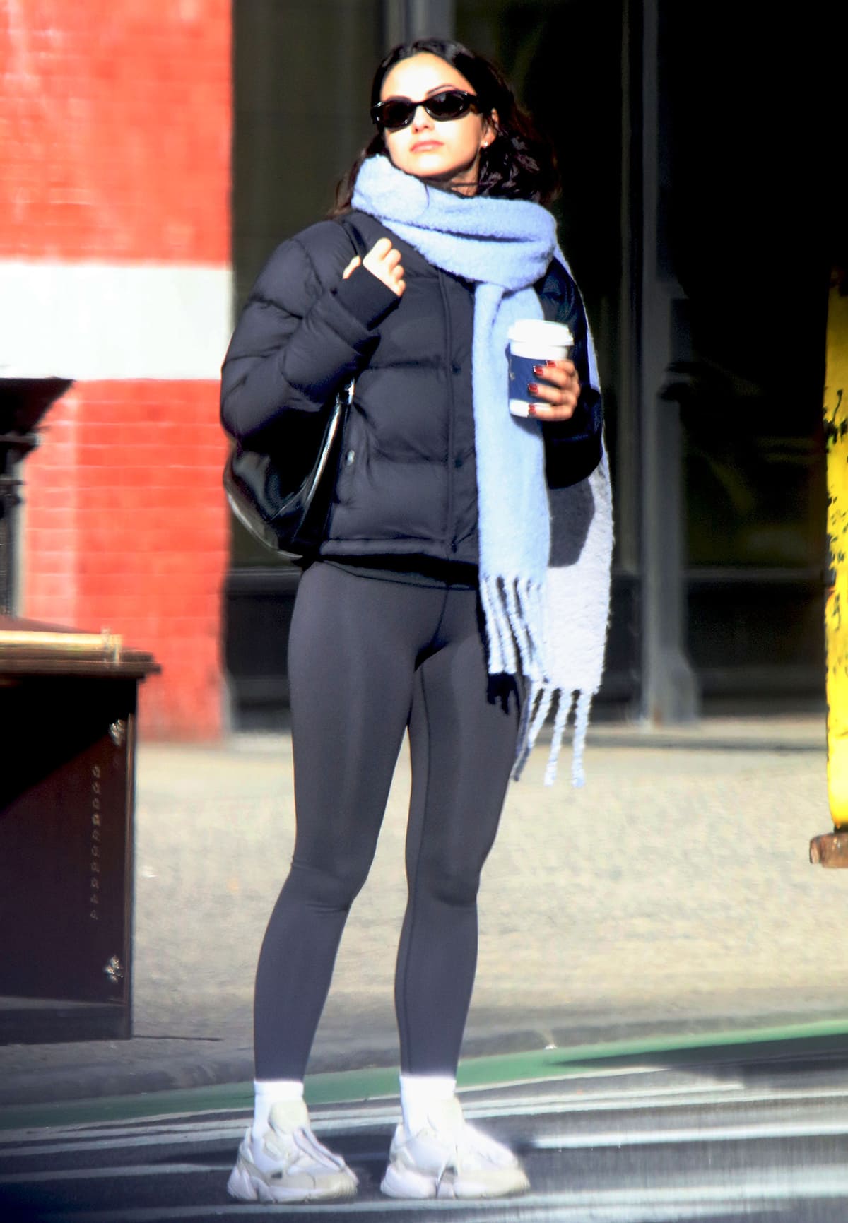 Camila Mendes bundles up in the Tna Super Puff Shorty puffer jacket, a light blue scarf, and a pair of leggings while out and about in Noho on January 3, 2024