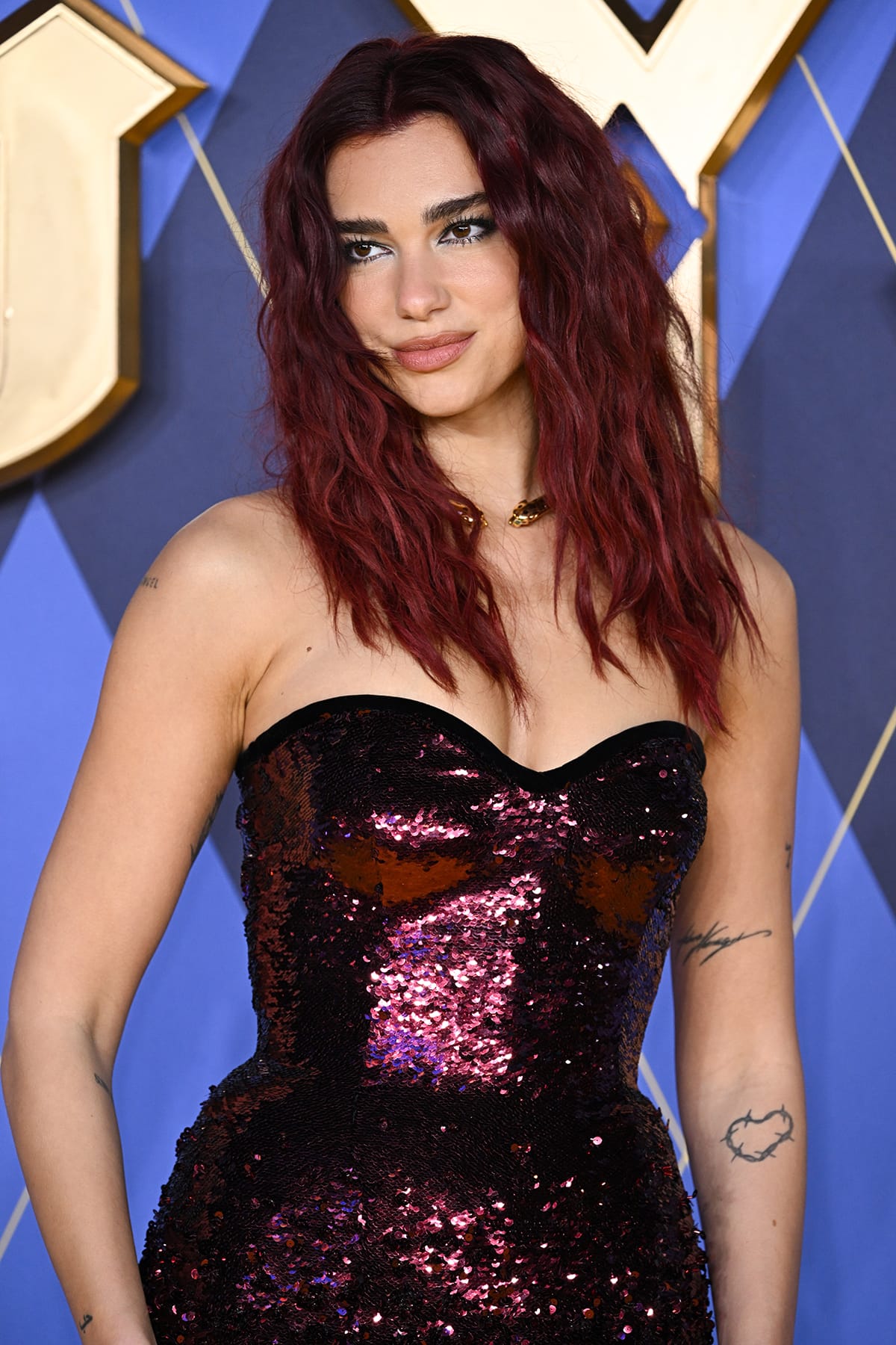Dua Lipa opts for a seductive vampy glam with a beach waves hairstyle, smokey eyeshadow, winged eyeliner, and nude pink lipstick