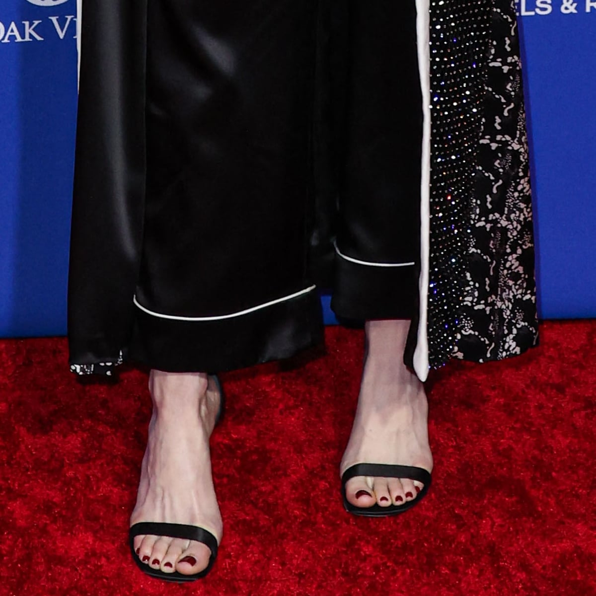 Emma Stone showcases her feet and impeccable taste in footwear with elegant Louis Vuitton strappy sandals accented by a deep rouge pedicure, adding a subtle yet sophisticated touch to her overall ensemble