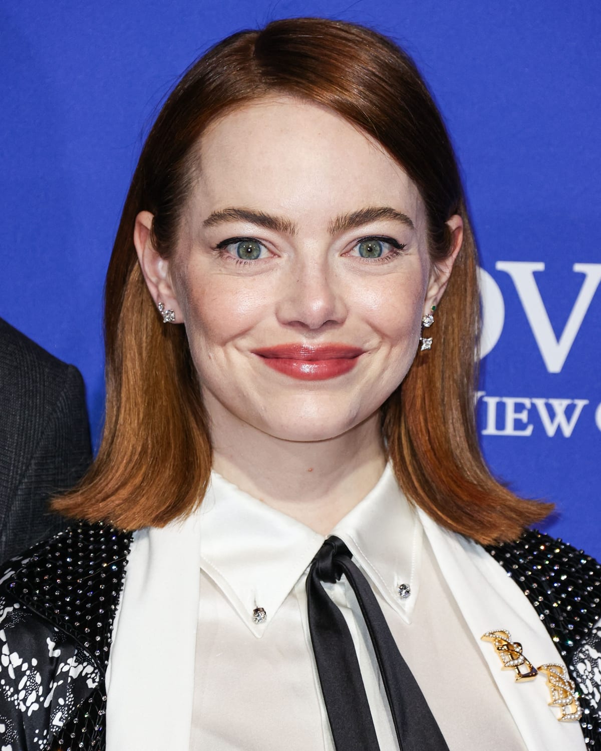 Emma Stone, the versatile actress from "The House Bunny," accessorizes her look with Louis Vuitton's gold and diamond ear studs and stylish gold brooches on her jacket