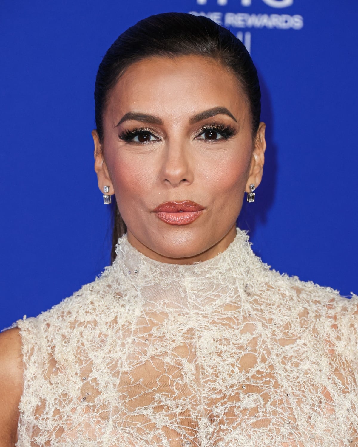 Glamour redefined: Eva Longoria's sleek low ponytail, silver eyeshadow, and glossy pink lip add the perfect finishing touches, embodying timeless beauty at the Palm Springs International Film Festival