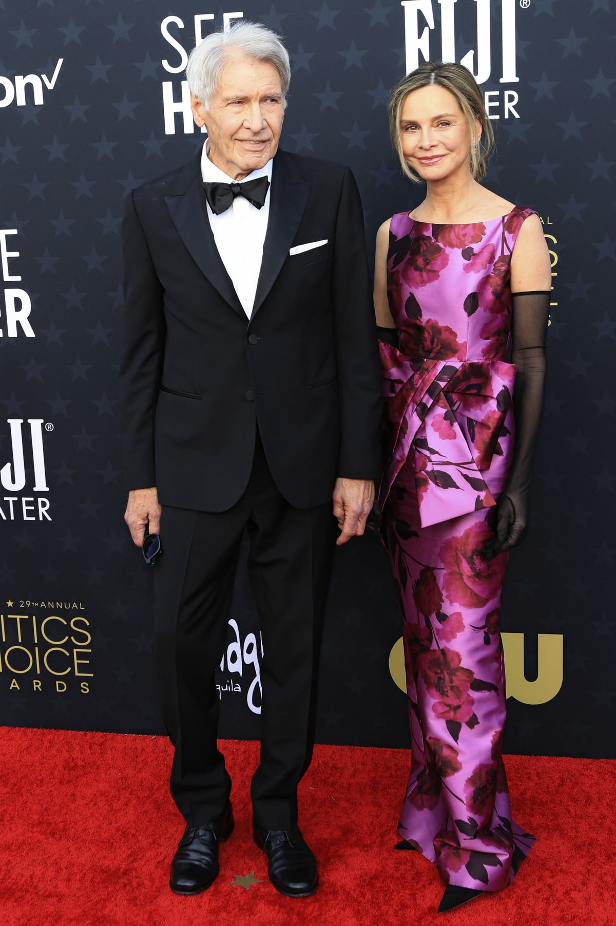 At the 2024 Critics Choice Awards, Harrison Ford and Calista Flockhart showcase their timeless style, with Ford in a classic tuxedo and Flockhart in a floral Erdem gown