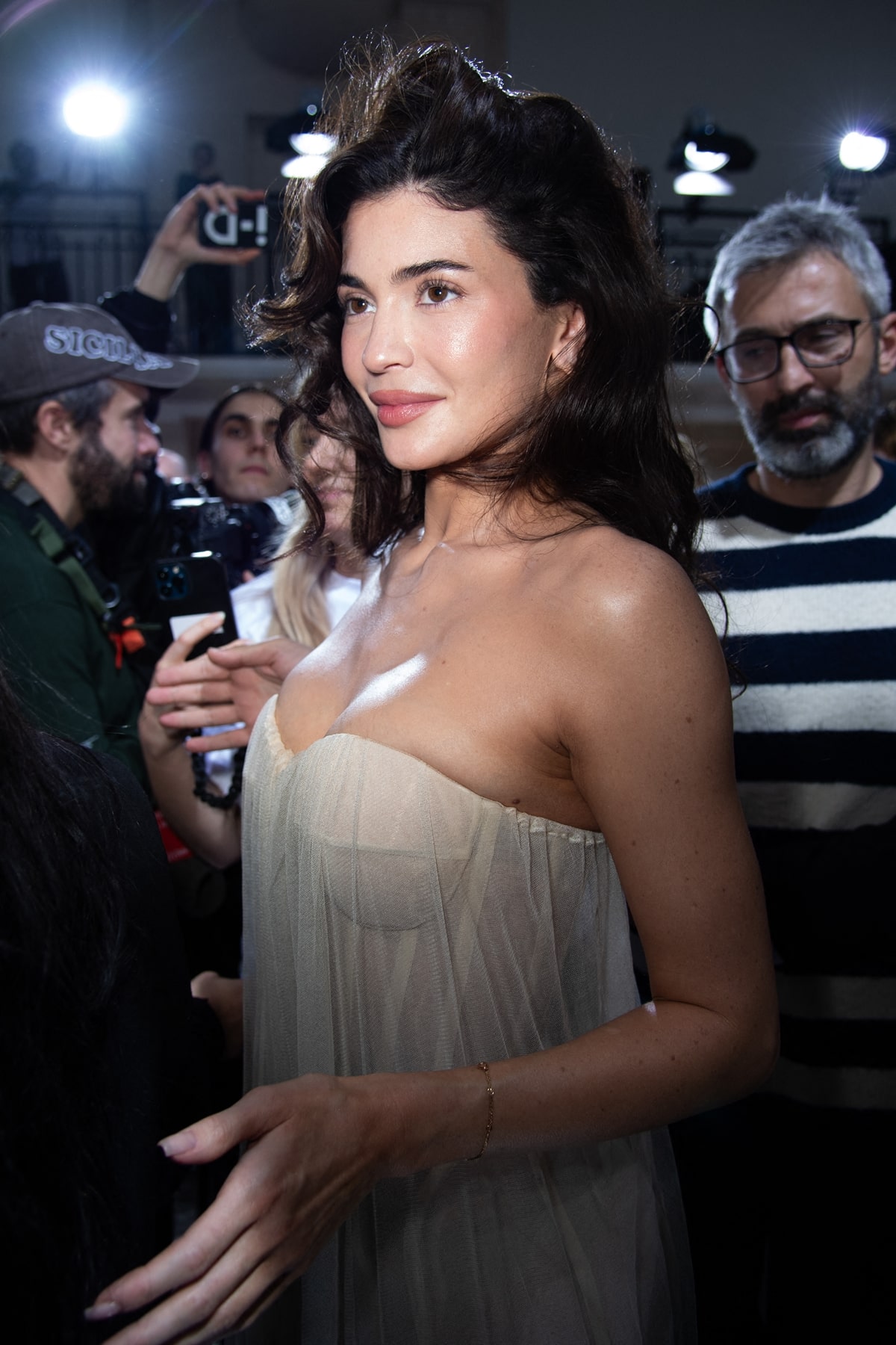 At the Jean Paul Gaultier show, Kylie Jenner captivates with a sheer strapless dress, complete with pearl-adorned heels and luscious curls, heralding a chic and sheer new era of style