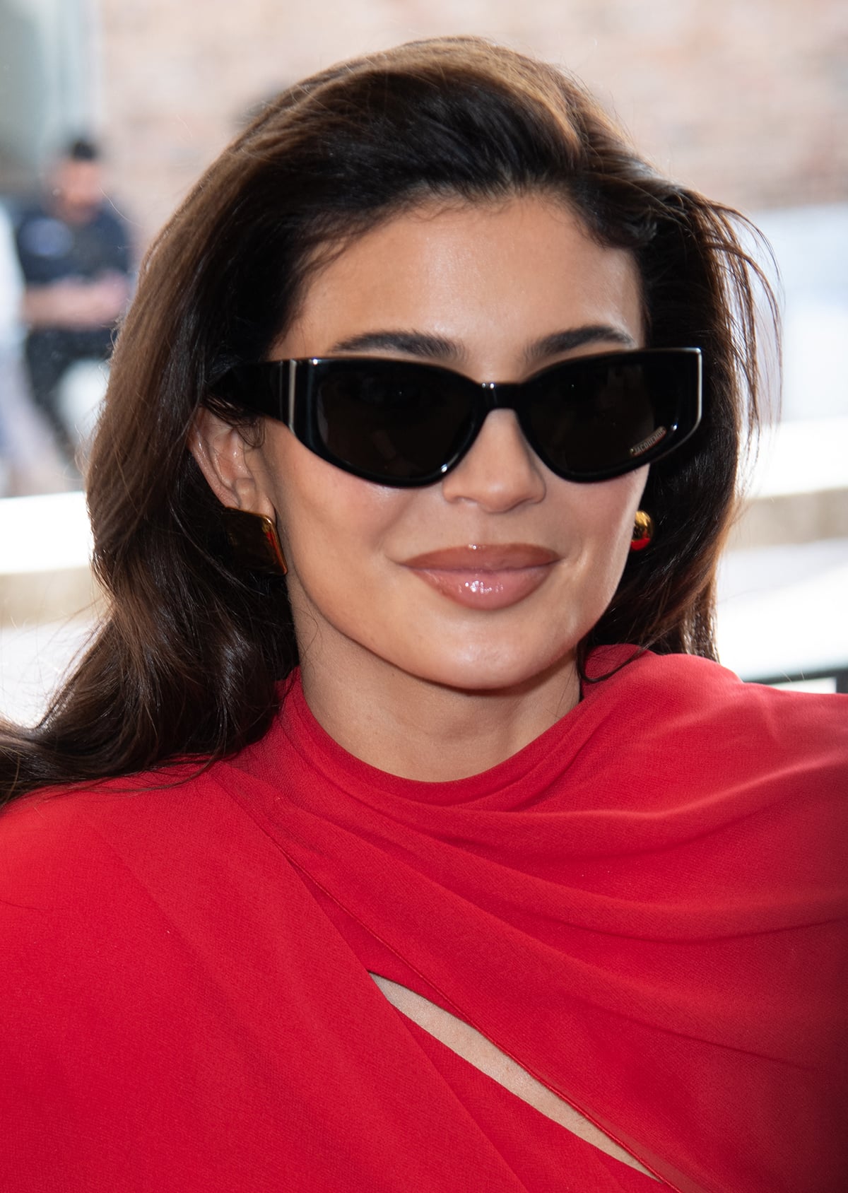 Wearing a retro backcombed hairstyle, Kylie Jenner styles her red Jacquemus draped minidress with Les Rond Carre mismatched earrings and black sunglasses