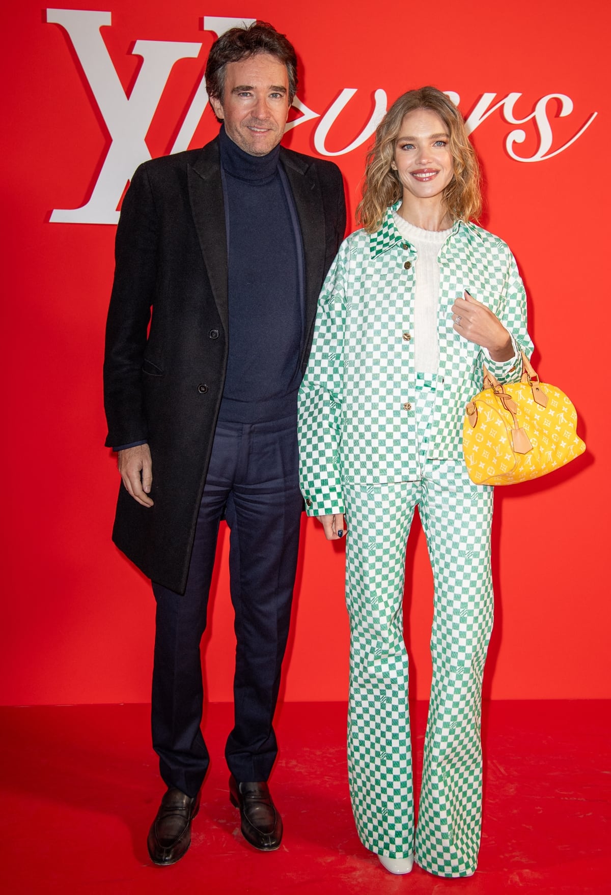 Natalia Vodianova radiated elegance at the Louis Vuitton event, posing with Antoine Arnault in a chic white and turquoise checkered ensemble, accented by a white high-neck sweater and a vibrant yellow handbag