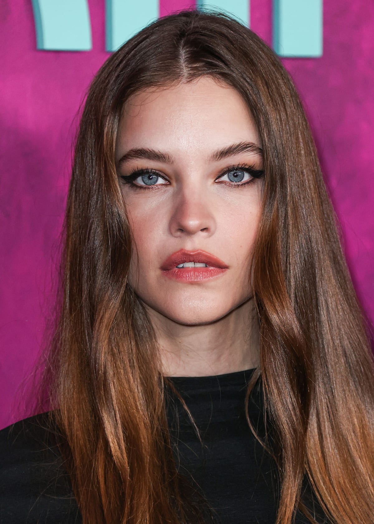 Barbara Palvin wears her long hair down and completes her gothic look with winged eyeliner, mascara, and peach lipstick