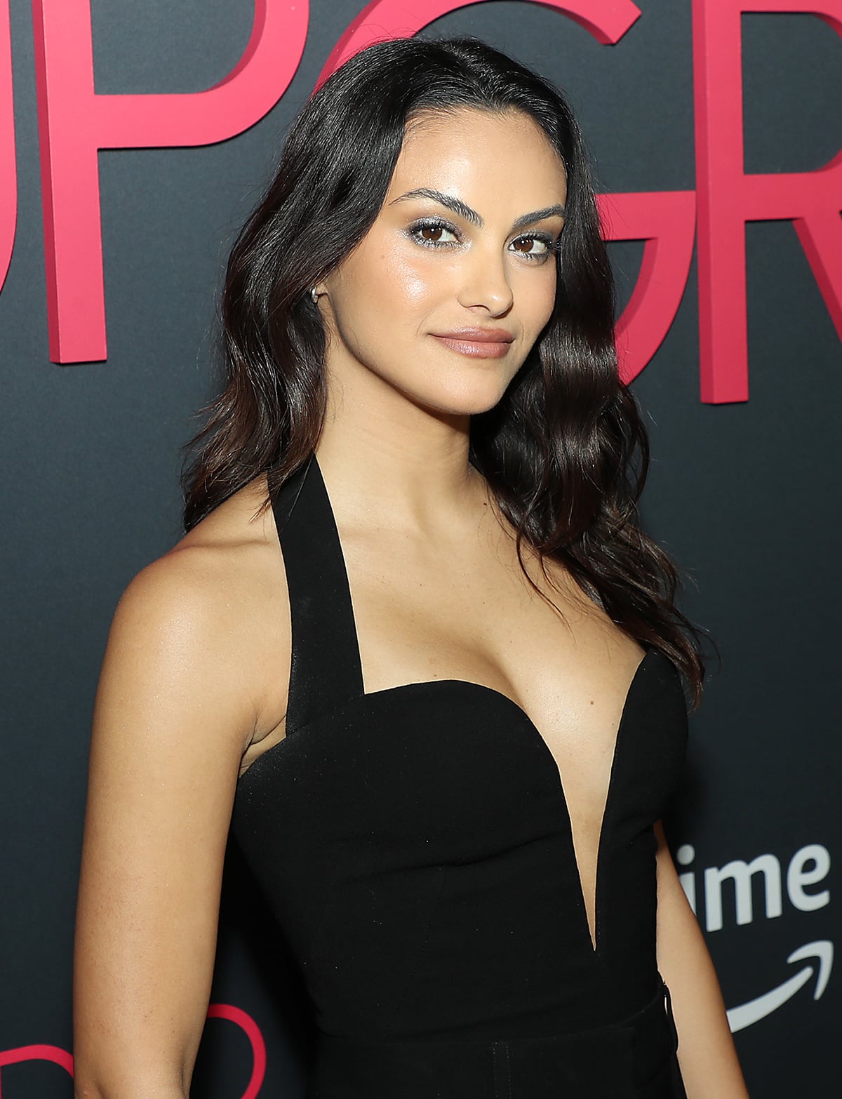 Camila Mendes styles her tresses in curls and wears metallic smoke makeup with nude lipstick