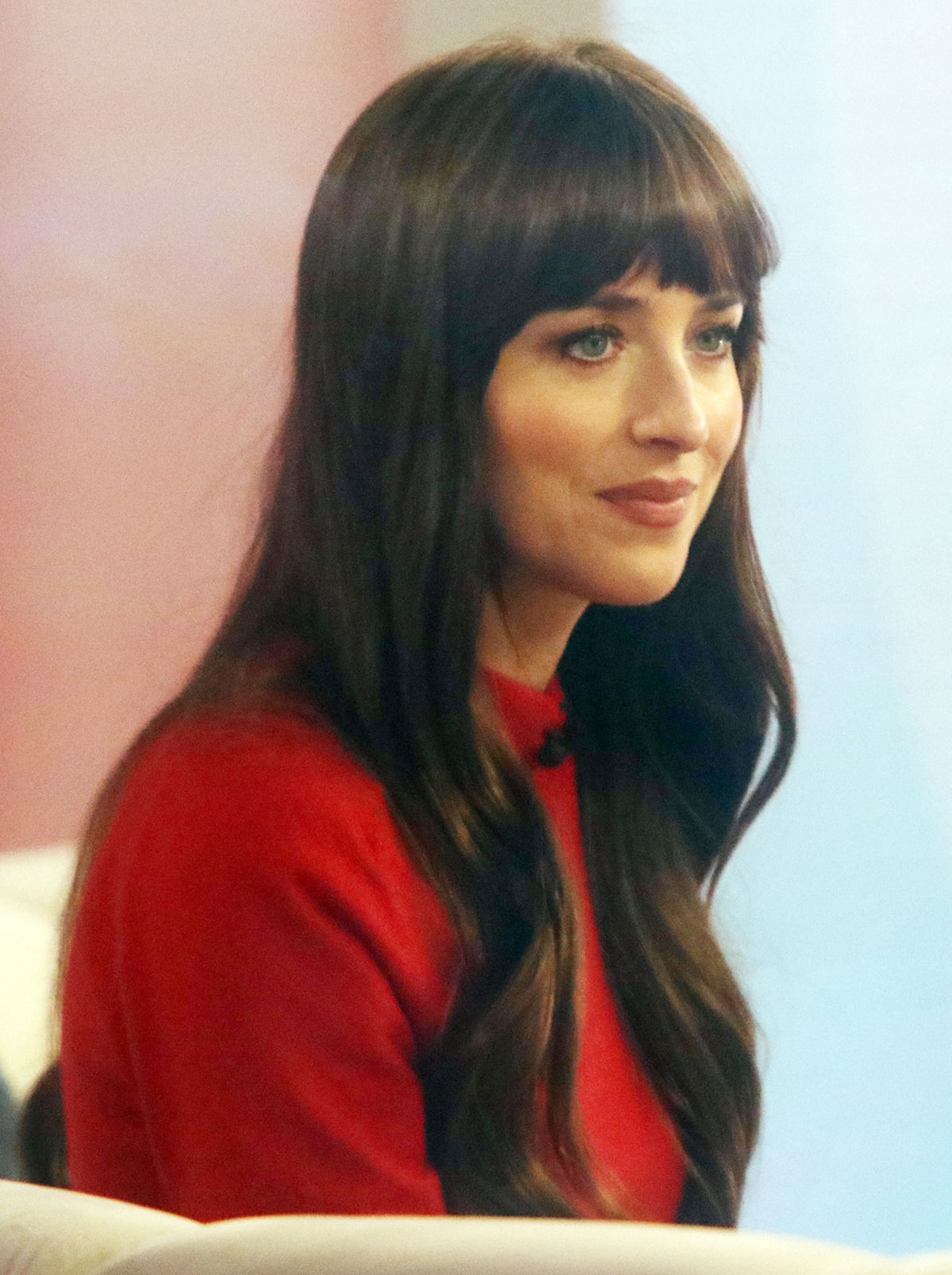 Dakota Johnson wears her signature bangs and completes her look with mascara and rosy makeup