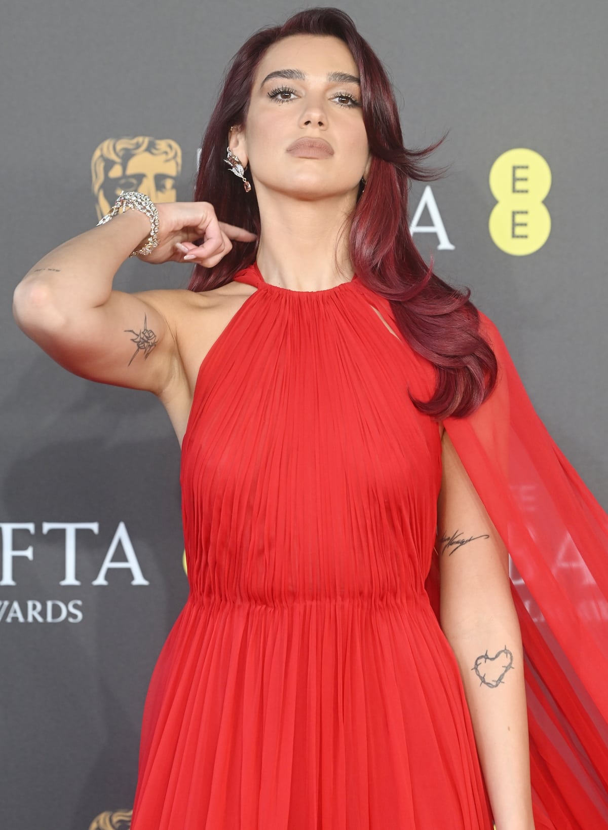 Dua Lipa's high-neck design of the dress gracefully showcased her subtle arm tattoos, while the form-fitting bodice highlighted her silhouette